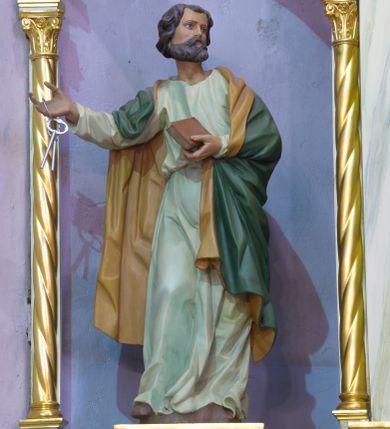 Zdjęcie nr 1: Rzeźba pełnoplastyczna, polichromowana, ustawiona na niewielkiej, prostopadłościennej podstawie. Święty Piotr ukazany całopostaciowo, w dynamicznej pozie z głową zwróconą w lewo oraz prawą ręką, w której trzyma pęk srebrnych kluczy, wyciągniętą w przed siebie. W lewej ręce, ugiętej w łokciu trzyma zamkniętą księgę w czerwonej oprawie. Święty przedstawiony jako dojrzały mężczyzna o ciemnych włosach oraz bujnym zaroście. Twarz szczupła z niewielkim, prostym nosem oraz wyraźnie zaznaczonymi kośćmi policzkowymi. Postać ubrana w długą jasnozieloną tunikę, na którą narzucony obszerny ciemnozielony płaszcz z żółtą podszewką.