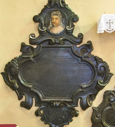 Zdjęcie nr 1: Epitafium z fantazyjnie wyciętą płyciną wpisaną w leżący prostokąt o bokach w kształcie półkolistych, nadwieszonych łukach na wklęsłych uskokach, ujętą uproszczonymi wolutami z chrząstkami. Pod dolną krawędzią kartusz z tarczą z godłami herbów Rawicz, Jastrzębiec, Ramułt, Korybut. Epitafium wieńczy owalne pole z portretem zmarłej otoczone ornamentem kartuszowo-zawijanym i zwieńczone krzyżem wspartym na trzech kulach. Kobieta została przedstawiona w popiersiu, w trzech czwartych, w koronkowym welonie oraz ze sznurem pereł na szyi. Twarz z migdałowatymi oczami zwróconymi w lewo, z długim nosem i wąskimi, szerokimi ustami. W polu inskrypcja „D(EO) O(PTIMO) M(AXIMO) / ET / HOMINVM MEMORIAE / G(E)N(ER)OSA CHRISTINA OLIM G(E)N(E)OSI GABRIELIS / A DEMBIANY DEMBINSKI CVM OLIM G(E)N(ER)OSA ISABELLA / A BELZEC BELZECKA PROCREATA / FILIA [obok wykutE wtórnie Primo CAROLI SZEMBEK 2do G(ENERO)SI ADAMI KOCHANSKI ultimo VOTO G(E)N(ER)OSI MATTHIAE ALEXANDRI A TARNOW TARNOWSKI VENATORIS PAL(A)TINI LANCICZE[SIS] / DVCATVS SEVERIAE CAPITANEI CASTRENSIS LEGITIMA / CONSORS / RELIGIONE IN DEVM CVLTV ET DEVOTIONE IN DEI PARAM AC DEI SANCTOS ERGA MARITVM / AC FILIOS AMORIS INTEGRITATE IN AMICOS AC VICINOS OFFICIO IN OMNES / MORVM PROBITATE INSIGNIS / MVLIER / CVM EXPLESSET ANNOS AETATES SVAE LVI MATRIMONIALIS / COHABITATIONIS XXXX DIE VI MARTII. A(NNO) D(OMINI) M.D.CXCV / SACRAMENTIS BENE MVNITA / IN VILLA GORENICE VITAM / FINIVIT. / LVGENS MARITIVS DESIDERATISSIMAE CONIVGI / HOC POSVIT MONVMENTVM / LECTOR / FIDELIBVS DEFVNCTIS / PRECARE / REQVIEM SEMPITERNAM.”