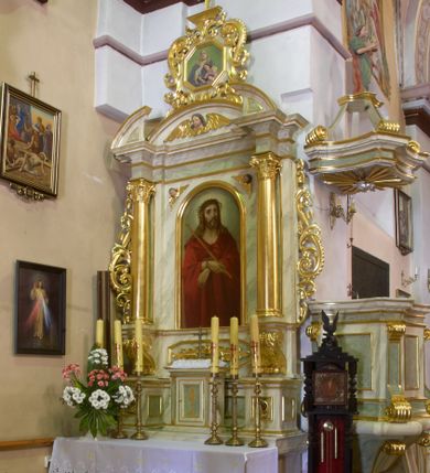 Zdjęcie nr 1: Ołtarz przyścienny, architektoniczny, jednoosiowy, jednokondygnacyjny ze zwieńczeniem. Mensa prostopadłościenna z antepedium drewnianym o dekoracji geometrycznej. W jego centrum okrągła płycina z obrazem Matki Boskiej Bolesnej ujęta po bokach dwiema kolejnymi płycinami w kształcie leżącego prostokąta o wklęsłym krótszym boku. Retabulum na wysokim cokole dekorowanym płyciną wypełnioną ornamentem małżowinowo-chrząstkowym, ujęte dwiema złoconymi kolumnami kompozytowymi ustawionymi na wolutowych konsolach i wysuniętymi nieco przed lico ołtarza. Kolumny dźwigają odcinki wyłamanego belkowania z wydatnym gzymsem oraz fragmenty tympanonu zamkniętego łukiem odcinkowym. W zwieńczeniu płaskorzeźbiona, uskrzydlona główka anielska na tle łuku odcinkowego oraz powyżej płaskorzeźbione przedstawienie sceny Nauczania Marii w ośmiobocznej, złoconej ramie ujętej ażurową strukturą ze złoconego ornamentu małżowinowo-chrząstkowego; całość zwieńczona złoconym krzyżem o trójlistnie zamkniętych ramionach. W głównym polu ołtarza płycina w kształcie stojącego prostokąta zamkniętego łukiem półokrągłym mieszcząca obraz Chrystusa w typie Ecce Homo w złoconej, profilowanej ramie. W przyłuczach dwie płaskorzeźbione, uskrzydlone główki anielskie. Ołtarz ujęty po bokach złoconymi, ażurowymi uszami utworzonymi z ornamentu małżowinowo-chrząstkowego. Na osi ustawione prostopadłościenne tabernakulum ujęte dwiema wolutami; na drzwiczkach malowany złotem kielich z hostią. Struktura ołtarza i tabernakulum polichromowana (w tym marmoryzowana) w odcieniach jasnej zieleni; detale elementów architektonicznych oraz ornamenty złocone.
