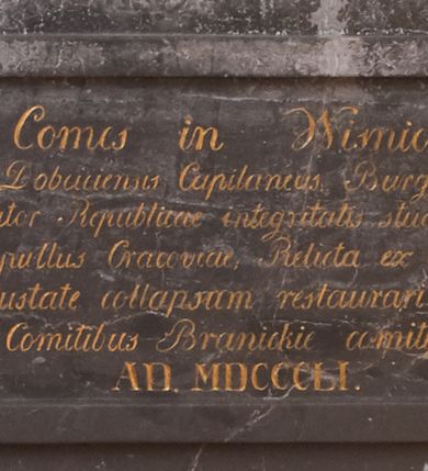 Zdjęcie nr 7: Nagrobek składa się z płyty w kształcie leżącego prostokąta i obramienia architektonicznego. Na płycie jest ukazany mężczyzna w zbroi w pozie na wpół leżącej, wsparty na ugiętej prawej ręce ułożonej na poduszce, ze zgiętymi i skrzyżowanymi nogami. Jego twarz jest przedstawiona frontalnie, oczy zamknięte, długi nos, z wyraźnie zarysowanymi brwiami i zmarszczkami na czole. Włosy ma krótkie, z kręconym lekko czubem, wąsy długie, sumiaste, broda krótka. Ubrany jest w zbroję płytową, z szarfą przewiązaną przez lewe ramię. Zbroja typu husarskiego, składająca się z napierśnika z dwoma folgami brzusznymi pod szyją zakończonego wałkiem w formie sznura, z trzyfolgowych naramienników, nałokci, z sześciofolgowych taszek przypiętych do pasa, nakolanników, nagolenników i butów z ostrogami. W prawej ręce trzyma buławę, lewą opiera na udzie. Przy boku widnieje szabla, a w tle panoplia – topór, miecz, szabla, tarcza i hełm.  
Obramienie wsparte na czterech konsolach – dwóch przyściennych i dwóch wysuniętych, dźwigających cokół z inskrypcją i dwie kolumny przewiązane w połowie opaską z romanizującymi kapitelami. Wieńczący obramienie trójkątny przyczółek jest ujęty kaboszonami i liściastymi akroterionami, a zwieńczony uproszczoną szyszką. W tympanonie wypełnionym wicią roślinną tarcza z godłem herbu Drużyna, zwieńczona hełmem z koroną.     
Na podstawie obramienia inskrypcja &quot;Sebastianus Comes in Wisnicz Lubomirski / Castellanus Woynicensis Sandomiriensis Scepusiensis, Dobciciensis Capitaneus Burgrab(ius) Cracov(iensis) atque Zupparum salinarum Praefectus. / Antiqua fide et virtute Senator Republicae integritatis studiosysimus, Bello et pace clarus; / Obiit 20 Julii Anno MDCXIII aetatis 76; sepullus Cracoviae; Relicta ex conjuge Anna de Ruszcza Branicka progenie. / Monumentum hocce velustate collapsum restaurari atque hic poni curavit. Sophia de Comitibus Branickie comitissa Potocka. / A(NNO) D(OMINI) MDCCCLI&quot;. 