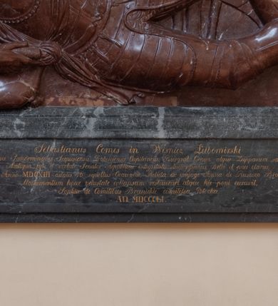 Zdjęcie nr 6: Nagrobek składa się z płyty w kształcie leżącego prostokąta i obramienia architektonicznego. Na płycie jest ukazany mężczyzna w zbroi w pozie na wpół leżącej, wsparty na ugiętej prawej ręce ułożonej na poduszce, ze zgiętymi i skrzyżowanymi nogami. Jego twarz jest przedstawiona frontalnie, oczy zamknięte, długi nos, z wyraźnie zarysowanymi brwiami i zmarszczkami na czole. Włosy ma krótkie, z kręconym lekko czubem, wąsy długie, sumiaste, broda krótka. Ubrany jest w zbroję płytową, z szarfą przewiązaną przez lewe ramię. Zbroja typu husarskiego, składająca się z napierśnika z dwoma folgami brzusznymi pod szyją zakończonego wałkiem w formie sznura, z trzyfolgowych naramienników, nałokci, z sześciofolgowych taszek przypiętych do pasa, nakolanników, nagolenników i butów z ostrogami. W prawej ręce trzyma buławę, lewą opiera na udzie. Przy boku widnieje szabla, a w tle panoplia – topór, miecz, szabla, tarcza i hełm.  
Obramienie wsparte na czterech konsolach – dwóch przyściennych i dwóch wysuniętych, dźwigających cokół z inskrypcją i dwie kolumny przewiązane w połowie opaską z romanizującymi kapitelami. Wieńczący obramienie trójkątny przyczółek jest ujęty kaboszonami i liściastymi akroterionami, a zwieńczony uproszczoną szyszką. W tympanonie wypełnionym wicią roślinną tarcza z godłem herbu Drużyna, zwieńczona hełmem z koroną.     
Na podstawie obramienia inskrypcja "Sebastianus Comes in Wisnicz Lubomirski / Castellanus Woynicensis Sandomiriensis Scepusiensis, Dobciciensis Capitaneus Burgrab(ius) Cracov(iensis) atque Zupparum salinarum Praefectus. / Antiqua fide et virtute Senator Republicae integritatis studiosysimus, Bello et pace clarus; / Obiit 20 Julii Anno MDCXIII aetatis 76; sepullus Cracoviae; Relicta ex conjuge Anna de Ruszcza Branicka progenie. / Monumentum hocce velustate collapsum restaurari atque hic poni curavit. Sophia de Comitibus Branickie comitissa Potocka. / A(NNO) D(OMINI) MDCCCLI". 