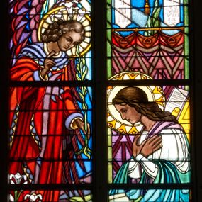 Zdjęcie nr 1: Witraż w trzecim przęśle od zachodu, w oknie południowym. Kompozycja w kształcie stojącego prostokąta zamkniętego łukiem ostrym, podzielona pionową laską na dwie części, u góry z maswerkiem o motywie czteroliścia. W prawej części ukazana Maria siedząca z dłońmi złożonymi na piersi. W lewej archanioł Gabriel w czerwonej szacie, z fioletowymi skrzydłami i lilią w lewej ręce; prawą rękę wznosi w geście pozdrowienia. Maria ubrana w zielono- błękitną szatę. Nad głową anioła Gołębica Ducha Świętego, od której spływają promienie. W tle wnętrze z fioletową kotarą, nad którą wiszą tablice Dziesięciu Przykazań i świecznik trójramienny. W polu czteroliścia u góry splecione litery imienia Maria. U dołu dekoracyjna rama wypełniona ornamentem geometrycznym, wewnątrz której dwa napisy: ANDREAS ET HEDWIGIS GŁOWNIA / CURA PAROCHI JACOBI MORAJKA / FUNDAVERUNT A. D. 1937; SUMPTIBUS PAROCHIANIS/ ANNO DOMINI- 1955/ RENOVATUM. Żywa kolorystyka, silny linearyzm, płaski modelunek.