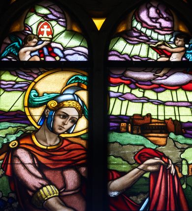 Zdjęcie nr 1: Witraż w prezbiterium w oknie północnym, w kształcie stojącego prostokąta zamkniętego łukiem ostrym. Kompozycja podzielona pionową laską na dwie części, u góry maswerk o motywie czteroliścia. Brak kwater nr 4, 5, 7 i 9 (od góry).  W centrum przedstawienie św. Marcina z Tours jadącego na koniu i oddającego część swojego płaszcza biedakowi. Święty ubrany w zbroję rzymską. W tle pejzaż z elementami architektury. Ponad głową postaci putto trzymające w dłoniach infułę biskupią oraz drugie z księgą. W polu czteroliścia anioł z trąbą. Całość stylizowana na gobelin z dekoracyjnymi chwostami u dołu. W 8 kwaterze napis: PIAE MEMORIAE PARENTUM LADISLAI ET MARIAE / FUNDAVIT A.D. 1938. (napis niekompletny, dalsza część znajdowała się w kwaterze nr 9).