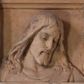 Zdjęcie nr 1: Płaskorzeźba w kształcie stojącego prostokąta z przedstawieniem w popiersiu Chrystusa Miłosiernego ujętego od dołu i od góry poziomymi listwami. Chrystus ukazany frontalnie, z głową lekko pochyloną i przechyloną na lewy bark. Twarz pociągła, z wydatnym nosem, wpółprzymkniętym oczami i wzrokiem skierowanym w dół; z wąsami i krótką, rozdwojoną na końcu brodą. Włosy długie, pofalowane, opadające na ramiona okryte cienką suknią z półkolistym wycięciem pod szyją. U góry na profilowanej belce inskrypcja majuskułą po polsku: O JEZU, z krót MÓJ MIŁOSIERDZIA!  Na dolnej listwie inskrypcja: Fund. Parochus Jacobus M(orajka) 1933. Całość pomalowana w kolorze jasnego beżu z przetarciami warstwy malarskiej.