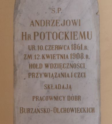 Zdjęcie nr 1: Tablica epitafijna dla upamiętnienia Andrzeja Potockiego, w formie wmurowanej w ścianę płyty kamiennej o kształcie prostokąta zamkniętego łukiem ostrym. W polu tablicy inskrypcja złoconą majuskułą, w języku polskim: Ś. P. / ANDRZEJOWI / HR. POTOCKIEMU / UR.10. CZERWCA 1861. R. / ZM. 12. KWIETNIA 1908. R. / HOŁD WDZIĘCZNOŚCI, / PRZYWIĄZANIA I CZCI / SKŁADAJĄ / PRACOWNICY DÓBR / BURZAŃSKO-OLCHOWIECKICH. Ponad inskrypcją znajduje się wykuty łaciński krzyż, poniżej inskrypcji herb Potockich: Pilawa.