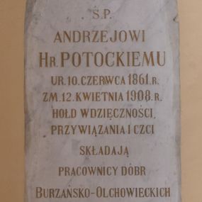 Zdjęcie nr 1: Tablica epitafijna dla upamiętnienia Andrzeja Potockiego, w formie wmurowanej w ścianę płyty kamiennej o kształcie prostokąta zamkniętego łukiem ostrym. W polu tablicy inskrypcja złoconą majuskułą, w języku polskim: Ś. P. / ANDRZEJOWI / HR. POTOCKIEMU / UR.10. CZERWCA 1861. R. / ZM. 12. KWIETNIA 1908. R. / HOŁD WDZIĘCZNOŚCI, / PRZYWIĄZANIA I CZCI / SKŁADAJĄ / PRACOWNICY DÓBR / BURZAŃSKO-OLCHOWIECKICH. Ponad inskrypcją znajduje się wykuty łaciński krzyż, poniżej inskrypcji herb Potockich: Pilawa.