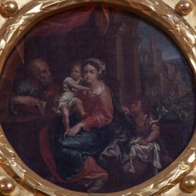 Zdjęcie nr 1: Obraz w kształcie koła (tondo) z przedstawieniem Świętej Rodziny. Pośrodku kompozycji ukazana Matka Boska w pozycji siedzącej, która podtrzymuje stojące na jej kolanach Dzieciątko, lewą ręką ujmując go za nóżkę. Ubrana w szeroką, czerwoną suknię z białym kołnierzem oraz szafirowy płaszcz. Dzieciątko, przewiązane w pasie białą pieluszką, obejmuje Marię za szyję. Po lewej siedzi święty Józef zwrócony ku scenie środkowej. Święty odziany w niebieską suknię i czerwony płaszcz. Po drugiej stronie, obok Marii, aniołek. Ponad postaciami podwieszona czerwona draperia. W tle pejzaż z widokiem Jerozolimy i niebieskie niebo. Obraz ujęty w ramę z wieńca laurowego, otoczonego ażurowym ornamentem o motywie okuciowym, z kwiatonami po bokach i krzyżem w muszli na szczycie.