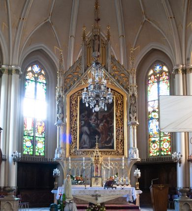 Zdjęcie nr 5: Ołtarz architektoniczny, przyścienny, jednokondygnacyjny, ze zwieńczeniem. Antependium prostokątne, zdobione płycinami z motywami maswrków. Nastawa jednoosiowa, z wydzieloną predellą, w której trzy prostokątne płyciny z dekoracją motywami maswerków, flankowana dwoma nadwieszonymi na konsolach, wielobocznym filarami, na których rzeźby uskrzydlonych aniołów stojących pod baldachimami zwieńczonymi pinaklami. W polu środkowym retabulum nisza prostokątna zamknięta łukiem odcinkowym, ujęta złoconą profilowaną ramą, w której w ażurowym rzeźbionym obramieniu obraz Hołd Trzech Króli. Zwieńczenie ołtarza dwustrefowe, trójkątne, ażurowe, z motywami maswerków, na osi z rodzajem aedikuli flankowanej pinaklami, w której rzeźba świętego Marcina pod baldachimem z pinaklem.