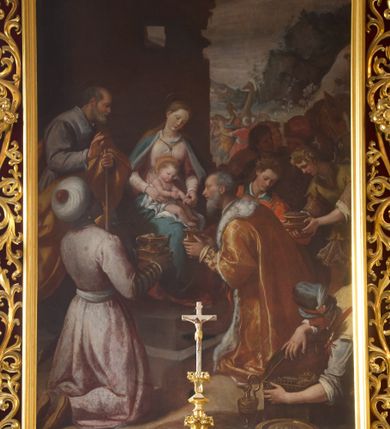Zdjęcie nr 1: W środku kompozycji Maria w jasnej sukni, z niebieskim płaszczem narzuconym na ramiona i odkrytą głową siedzi, trzymając nagie Dzieciątko na kolanach. Obok niej po lewej stronie stoi św. Józef zwrócony profilem, wsparty na lasce. Na pierwszym planie Trzej Królowie: z lewej Murzyn w turbanie odwrócony tyłem klęczy, podając szkatułkę, pośrodku, zwrócony profilem klęczy brodaty monarcha w aksamitnym złotym płaszczu i podaje Dzieciątku naczynie. Trzeci król w czapce z piórem ukazuje się w prawym dolnym narożniku, pochylony otwiera szkatułę z darami. Na drugim planie po prawej grupa dwóch giermków z naczyniem. W tle po lewej architektura ruin, po prawej daleki „romantyczny” krajobraz. Koloryt soczysty, odpowiadający w tonacji wieczornej porze sceny.