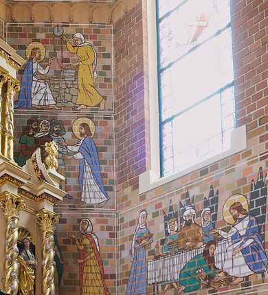 Zdjęcie nr 3: Polichromia, kładziona bezpośrednio na cegłę, pokrywa ściany oraz sklepienie świątyni – na ścianach namalowano sceny figuralne, na sklepieniu dekorację floralną.  Poszczególne sceny na ścianach są ujęte w cienkie białe ramy. Przedstawienia są schematyczne, linearne i obwiedzione konturem. 
Na ścianach prezbiterium od strony północnej przedstawienie Ostatniej Wieczerzy. Chrystus w centrum siedzi na tronie, prawa dłoń uniesiona w geście błogosławieństwa, lewa spoczywa na stole, przed nim kielich i chleb, wokół głowy nimb. Obok Chrystusa symetrycznie rozmieszczeni apostołowie tworzący cztery grupy złożone z trzech apostołów każda. Po przeciwnej stronie scena Zesłania Ducha Świętego. W centrum klęcząca frontalnie Matka Boska, w nimbie wokół głowy, nad nią gołębica Ducha Świętego w glorii. Postać Matki Boskiej i otaczający apostołowie z językami ognia. Powyżej obu przedstawień prostokątne zakończone ostrołukowo płyciny wypełnione w górnej części linearnymi przedstawieniami świętych na białym tle. Na północnej ścianie prezbiterium św. Stanisław Kostka ukazany całopostaciowo, zwrócony w lewą stronę, w habicie przewiązanym sznurem w pasie i w płaszczu. W lewej dłoni trzyma krucyfiks, a w prawej lilię; wokół głowy nimb. U dołu napis: „ŚW. STANISŁAW KOSTKA” . Po przeciwnej stronie bł. Maria Goretti. Postać jest zwrócona w prawą stronę, ubrana w sukienkę i chustę na ramionach, dłonie złożone na piersi, w prawej trzyma palmę męczeństwa. U dołu napis „bł. Maria G[?]oretti” 
Apsyda: 
W najniższym pasie od lewej strony scena Zmartwychwstania. W centrum Chrystus wychodzący z grobu,  ukazany frontalnie, ubrany w czerwony płaszcz, spięty pod szyją, prawa dłoń uniesiona w geście błogosławieństwa, w lewej chorągiew paschalna. Po prawej stronie ukazany siedzący na kamieniu grobowym anioł zwrócony w stroną Chrystusa. Po lewej stojące trzy niewiasty, w dłoniach trzymające naczynia. Wokół głów Chrystusa i anioła nimby. 
Scena przedstawiająca Wieczerzę w Emaus ukazuje trzy postacie siedzące przy stole. Chrystus po lewej stronie, profilem, z prawą dłonią uniesioną w geście błogosławieństwa, w lewej trzymający kulę. Po prawej stronie przedstawieni apostołowie z uniesionymi rękami. Na stole kielich z winem i bochenek chleba. Wszystkie postaci siedzą na krzesłach z wysokimi zapleckami. 
W scenie przedstawiającej wizytę Zbawiciela u Marii i Marty, Chrystus ukazany z prawej strony, z profilu, siedzi na krześle z wysokim zapieckiem, zwrócony w stronę Marii. Prawa dłoń uniesiona w geście oratorskim, lewa spoczywa na kolanie. Maria klęcząca przed Jezusem jest ukazana z profilu. Na drugim planie fragment stołu, na którym stoi biały wazon i bochenek chleba. Z lewej strony postać Marty ukazana frontalnie, z głową skierowaną w stronę Chrystusa, z dłońmi trzymającymi misę. 
W scenie przedstawiającej Złożenie do grobu, w centrum znajduje się Maria trzymająca na kolanach ciało syna, podtrzymywane dodatkowo przez dwie kobiety. Wokół grupy trzy postacie adorujących kobiet. 
 W wyższym rzędzie od lewej strony scena przedstawiająca Wskrzeszenia Łazarza. Z prawej strony stojący Łazarz w śmiertelnym zawoju, po jego lewej stronie Chrystus ukazany niemal profilem, z uniesionymi dłońmi. Za Chrystusem cztery postaci, trzy kobiety i mężczyzna, jedna z kobiet klęczy. 
W kolejnej scenie wyobrażono Jezusa zwróconego w lewo, w stronę św. Piotra, z lewą dłonią wzniesioną do góry i z prawą trzymającą dwa klucze, które przekazuje Piotrowi. Przed nim klęczący, ukazany z profilu św. Piotr, odbierający klucze lewą dłonią. Na drugim planie, za postacią Piotra, stoi dwóch mężczyzn. 
W scenie przedstawiającej przypowieść o talentach, ukazane są cztery kobiety. Z prawej strony kobieta zwrócona w prawą stronę, prawa ręka uniesiona, w dłoni moneta. Z lewej strony, grupa trzech poruszonych kobiet. 
Scena ukazująca Umywanie nóg Chrystusowi przez Marię Magdalenę przedstawia siedzącego Chrystusa zwróconego w prawo, w kierunku klęczącej Marii Magdaleny. Kobieta wyciera jego stopy włosami, obok pojemnik na oleje. Na drugim planie suto zastawiony stół biesiadny, przy nim siedzą trzy postacie umieszczone symetrycznie, w centrum mężczyzna, po jego bokach kobiety. Z lewej strony, stojąca kobieta z misą. 
W trzecim rzędzie od lewej scena przedstawiająca rozmnożenie chleba i ryb. Z prawej strony siedzący Chrystus, ukazany z profilu, zwrócony w prawą stronę. Z dłońmi uniesionymi nad koszem, pełnym ułomków chleba. Przed nim dziecko w prawej dłoni trzymające kosz, w lewej dwie ryby. Za dzieckiem przedstawiono dwóch stojących mężczyzn zwróconych w stronę Chrystusa. 
Kolejna scena przedstawia uzdrowienie chorego. Z prawej strony stojący Chrystus, ukazany z profilu z uniesionymi dłońmi. Z lewej strony grupa trzech osób – kobieta podtrzymywana przez dwóch mężczyzn. 
W następnym rzędzie od lewej scena przedstawiająca Chrystusa z dwoma mężczyznami. Jezus po lewej stronie, ukazany z profilu, zwrócony w lewą stronę, prawa dłoń uniesiona w geście oratorskim. Z prawej strony dwóch kroczących mężczyzn.
następna scena z Barankiem Apokaliptycznym.  W centrum ustawiony jest ołtarz, na którym stoi kielich, nad nim na księdze z siedmioma pieczęciami spoczywa baranek w glorii. Z lewej strony św. Jan Ewangelista, zwrócony w stronę baranka, w lewej dłoni otwarta księga, w prawej pióro. Z prawej strony ustawiony frontalnie św. Jan Chrzciciel, w lewej dłoni trzyma krzyż na długim drzewcu, wokół głów nimby. 
Kolejna scena przedstawia Chrystusa z Samarytanką. Po lewej stronie Jezus siedzący przy studni, ukazany z profilu, zwrócony w lewą stronę, lewa ręka uniesiona, prawa spoczywa na kolanie. Z prawej strony Samarytanka zwrócona w stronę Chrystusa, czerpiąca wodę ze studni. 
W zwieńczeniu prezbiterium od lewej strony św. Andrzej ukazany całopostaciowo, frontalnie, w pomarańczowej tunice, brązowym płaszczu, w lewej ręce ma zamkniętą księgę i pióro gęsie, w prawej podtrzymuje krzyż, wokół głowy nimb. 
W środkowej scenie znajduje się Matka Boska z Dzieciątkiem ukazana całopostaciowo, frontalnie. Maria w białej sukni, niebieskim płaszczu i czerwonych trzewiczkach, na lewym ramieniu trzyma Dzieciątko Jezus ubrane w czerwoną tunikę, prawą dłoń unosi w geście błogosławieństwa, w lewej trzyma jabłko królewskie. Wokół głów nimby.  Po bokach napisy „AVE / MARIA / GRATIA / PLENA”.  
Z prawej strony św. Maria Magdalena ukazana całopostaciowo, frontalnie, w zielonej sukni, pomarańczowym płaszczu, białym welonie na głowie, w prawej dłoni trzyma otwartą księgę, na niej trupia czaszka, na której spoczywa lewa dłoń. Wokół głowy nimb. 
Na ścianie przy łuku tęczowym po stronie północnej przedstawiono  biskupów  św. Stanisława i  św. Wojciecha. Ukazani frontalnie, całopostaciowo, obaj w pełnym stroju biskupim, w lewych dłoniach pastorały, wokół głów nimby. Święty Stanisław z paliuszem na ramionach, prawa dłoń w geście błogosławieństwa, św. Wojciech w rękawiczkach, w prawej dłoni zamknięta księga. U dołu tarcze herbowe, nad nimi napisy „ŚWIETY STANISŁAW BISKUP / ŚWIETY WOJCIECH BISKUP”. 
Na sklepieniach w nawie głównej, prezbiterium i absydzie w polach wydzielanych czerwonym konturem, dekoracja w formie bujniej wici roślino-kwiatowej. W nawie główniej rzadsza. Łuk tęczowy z barwionymi kształtkami – czerwień, pomarańcz, zieleń, granat. Sklepienia naw bocznych – w polach wydzielanych czerwonym konturem, dekoracja w formie symetrycznych dekoracyjnych wstążek, żółto-niebieskich. Sklepienia empor błękitne. 
Ściana chóru – balustrada, w przyłączach wić akantowa, tło groszkowane, na balustradzie przedstawienia dam i królów, na osi godło Polski wyżej napis „966”, postacie ukazane w popiersiu, oddzielone kwiatonami, tło cętkowane. Ściana chórowa z symetrycznym przedstawianiem aniołów w locie, w długich rozwianych szatach, przy pasach falujące wstążki. Anioł po lewej dmący w trąbkę, po prawej oburącz trzyma skrzypce.
