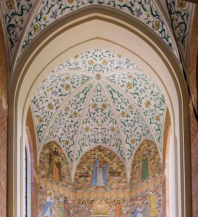 Zdjęcie nr 1: Polichromia, kładziona bezpośrednio na cegłę, pokrywa ściany oraz sklepienie świątyni – na ścianach namalowano sceny figuralne, na sklepieniu dekorację floralną.  Poszczególne sceny na ścianach są ujęte w cienkie białe ramy. Przedstawienia są schematyczne, linearne i obwiedzione konturem. 
Na ścianach prezbiterium od strony północnej przedstawienie Ostatniej Wieczerzy. Chrystus w centrum siedzi na tronie, prawa dłoń uniesiona w geście błogosławieństwa, lewa spoczywa na stole, przed nim kielich i chleb, wokół głowy nimb. Obok Chrystusa symetrycznie rozmieszczeni apostołowie tworzący cztery grupy złożone z trzech apostołów każda. Po przeciwnej stronie scena Zesłania Ducha Świętego. W centrum klęcząca frontalnie Matka Boska, w nimbie wokół głowy, nad nią gołębica Ducha Świętego w glorii. Postać Matki Boskiej i otaczający apostołowie z językami ognia. Powyżej obu przedstawień prostokątne zakończone ostrołukowo płyciny wypełnione w górnej części linearnymi przedstawieniami świętych na białym tle. Na północnej ścianie prezbiterium św. Stanisław Kostka ukazany całopostaciowo, zwrócony w lewą stronę, w habicie przewiązanym sznurem w pasie i w płaszczu. W lewej dłoni trzyma krucyfiks, a w prawej lilię; wokół głowy nimb. U dołu napis: „ŚW. STANISŁAW KOSTKA” . Po przeciwnej stronie bł. Maria Goretti. Postać jest zwrócona w prawą stronę, ubrana w sukienkę i chustę na ramionach, dłonie złożone na piersi, w prawej trzyma palmę męczeństwa. U dołu napis „bł. Maria G[?]oretti” 
Apsyda: 
W najniższym pasie od lewej strony scena Zmartwychwstania. W centrum Chrystus wychodzący z grobu,  ukazany frontalnie, ubrany w czerwony płaszcz, spięty pod szyją, prawa dłoń uniesiona w geście błogosławieństwa, w lewej chorągiew paschalna. Po prawej stronie ukazany siedzący na kamieniu grobowym anioł zwrócony w stroną Chrystusa. Po lewej stojące trzy niewiasty, w dłoniach trzymające naczynia. Wokół głów Chrystusa i anioła nimby. 
Scena przedstawiająca Wieczerzę w Emaus ukazuje trzy postacie siedzące przy stole. Chrystus po lewej stronie, profilem, z prawą dłonią uniesioną w geście błogosławieństwa, w lewej trzymający kulę. Po prawej stronie przedstawieni apostołowie z uniesionymi rękami. Na stole kielich z winem i bochenek chleba. Wszystkie postaci siedzą na krzesłach z wysokimi zapleckami. 
W scenie przedstawiającej wizytę Zbawiciela u Marii i Marty, Chrystus ukazany z prawej strony, z profilu, siedzi na krześle z wysokim zapieckiem, zwrócony w stronę Marii. Prawa dłoń uniesiona w geście oratorskim, lewa spoczywa na kolanie. Maria klęcząca przed Jezusem jest ukazana z profilu. Na drugim planie fragment stołu, na którym stoi biały wazon i bochenek chleba. Z lewej strony postać Marty ukazana frontalnie, z głową skierowaną w stronę Chrystusa, z dłońmi trzymającymi misę. 
W scenie przedstawiającej Złożenie do grobu, w centrum znajduje się Maria trzymająca na kolanach ciało syna, podtrzymywane dodatkowo przez dwie kobiety. Wokół grupy trzy postacie adorujących kobiet. 
 W wyższym rzędzie od lewej strony scena przedstawiająca Wskrzeszenia Łazarza. Z prawej strony stojący Łazarz w śmiertelnym zawoju, po jego lewej stronie Chrystus ukazany niemal profilem, z uniesionymi dłońmi. Za Chrystusem cztery postaci, trzy kobiety i mężczyzna, jedna z kobiet klęczy. 
W kolejnej scenie wyobrażono Jezusa zwróconego w lewo, w stronę św. Piotra, z lewą dłonią wzniesioną do góry i z prawą trzymającą dwa klucze, które przekazuje Piotrowi. Przed nim klęczący, ukazany z profilu św. Piotr, odbierający klucze lewą dłonią. Na drugim planie, za postacią Piotra, stoi dwóch mężczyzn. 
W scenie przedstawiającej przypowieść o talentach, ukazane są cztery kobiety. Z prawej strony kobieta zwrócona w prawą stronę, prawa ręka uniesiona, w dłoni moneta. Z lewej strony, grupa trzech poruszonych kobiet. 
Scena ukazująca Umywanie nóg Chrystusowi przez Marię Magdalenę przedstawia siedzącego Chrystusa zwróconego w prawo, w kierunku klęczącej Marii Magdaleny. Kobieta wyciera jego stopy włosami, obok pojemnik na oleje. Na drugim planie suto zastawiony stół biesiadny, przy nim siedzą trzy postacie umieszczone symetrycznie, w centrum mężczyzna, po jego bokach kobiety. Z lewej strony, stojąca kobieta z misą. 
W trzecim rzędzie od lewej scena przedstawiająca rozmnożenie chleba i ryb. Z prawej strony siedzący Chrystus, ukazany z profilu, zwrócony w prawą stronę. Z dłońmi uniesionymi nad koszem, pełnym ułomków chleba. Przed nim dziecko w prawej dłoni trzymające kosz, w lewej dwie ryby. Za dzieckiem przedstawiono dwóch stojących mężczyzn zwróconych w stronę Chrystusa. 
Kolejna scena przedstawia uzdrowienie chorego. Z prawej strony stojący Chrystus, ukazany z profilu z uniesionymi dłońmi. Z lewej strony grupa trzech osób – kobieta podtrzymywana przez dwóch mężczyzn. 
W następnym rzędzie od lewej scena przedstawiająca Chrystusa z dwoma mężczyznami. Jezus po lewej stronie, ukazany z profilu, zwrócony w lewą stronę, prawa dłoń uniesiona w geście oratorskim. Z prawej strony dwóch kroczących mężczyzn.
następna scena z Barankiem Apokaliptycznym.  W centrum ustawiony jest ołtarz, na którym stoi kielich, nad nim na księdze z siedmioma pieczęciami spoczywa baranek w glorii. Z lewej strony św. Jan Ewangelista, zwrócony w stronę baranka, w lewej dłoni otwarta księga, w prawej pióro. Z prawej strony ustawiony frontalnie św. Jan Chrzciciel, w lewej dłoni trzyma krzyż na długim drzewcu, wokół głów nimby. 
Kolejna scena przedstawia Chrystusa z Samarytanką. Po lewej stronie Jezus siedzący przy studni, ukazany z profilu, zwrócony w lewą stronę, lewa ręka uniesiona, prawa spoczywa na kolanie. Z prawej strony Samarytanka zwrócona w stronę Chrystusa, czerpiąca wodę ze studni. 
W zwieńczeniu prezbiterium od lewej strony św. Andrzej ukazany całopostaciowo, frontalnie, w pomarańczowej tunice, brązowym płaszczu, w lewej ręce ma zamkniętą księgę i pióro gęsie, w prawej podtrzymuje krzyż, wokół głowy nimb. 
W środkowej scenie znajduje się Matka Boska z Dzieciątkiem ukazana całopostaciowo, frontalnie. Maria w białej sukni, niebieskim płaszczu i czerwonych trzewiczkach, na lewym ramieniu trzyma Dzieciątko Jezus ubrane w czerwoną tunikę, prawą dłoń unosi w geście błogosławieństwa, w lewej trzyma jabłko królewskie. Wokół głów nimby.  Po bokach napisy „AVE / MARIA / GRATIA / PLENA”.  
Z prawej strony św. Maria Magdalena ukazana całopostaciowo, frontalnie, w zielonej sukni, pomarańczowym płaszczu, białym welonie na głowie, w prawej dłoni trzyma otwartą księgę, na niej trupia czaszka, na której spoczywa lewa dłoń. Wokół głowy nimb. 
Na ścianie przy łuku tęczowym po stronie północnej przedstawiono  biskupów  św. Stanisława i  św. Wojciecha. Ukazani frontalnie, całopostaciowo, obaj w pełnym stroju biskupim, w lewych dłoniach pastorały, wokół głów nimby. Święty Stanisław z paliuszem na ramionach, prawa dłoń w geście błogosławieństwa, św. Wojciech w rękawiczkach, w prawej dłoni zamknięta księga. U dołu tarcze herbowe, nad nimi napisy „ŚWIETY STANISŁAW BISKUP / ŚWIETY WOJCIECH BISKUP”. 
Na sklepieniach w nawie głównej, prezbiterium i absydzie w polach wydzielanych czerwonym konturem, dekoracja w formie bujniej wici roślino-kwiatowej. W nawie główniej rzadsza. Łuk tęczowy z barwionymi kształtkami – czerwień, pomarańcz, zieleń, granat. Sklepienia naw bocznych – w polach wydzielanych czerwonym konturem, dekoracja w formie symetrycznych dekoracyjnych wstążek, żółto-niebieskich. Sklepienia empor błękitne. 
Ściana chóru – balustrada, w przyłączach wić akantowa, tło groszkowane, na balustradzie przedstawienia dam i królów, na osi godło Polski wyżej napis „966”, postacie ukazane w popiersiu, oddzielone kwiatonami, tło cętkowane. Ściana chórowa z symetrycznym przedstawianiem aniołów w locie, w długich rozwianych szatach, przy pasach falujące wstążki. Anioł po lewej dmący w trąbkę, po prawej oburącz trzyma skrzypce.
