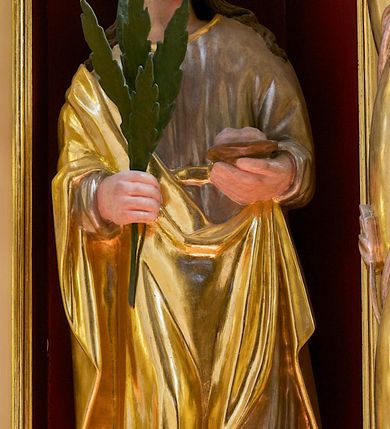 Zdjęcie nr 1: Figura pełna przedstawiająca nieokreśloną świętą męczennicę. Święta stoi frontalnie, spoglądając lekko w lewą stronę. Ma podłużną twarz, małe oczy, wąski nos, niewielkie usta i długie, ciemne włosy spływające falami na ramiona i plecy. W prawej ręce trzyma palmę męczeńską, w lewej trudny do określenia przedmiot umieszczony na podstawce. Ubrana jest w przepasaną, srebrną suknię wykończoną przy dekolcie złotą taśmą oraz złoty płaszcz, który przechodzi przez prawą rękę i jest podczepiony na lewym biodrze. 