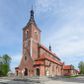 Zdjęcie nr 1: Kościół nieorientowany, skierowany prezbiterium ku północy, otoczony metalowym ogrodzeniem.  
Nawa na planie prostokąta z delikatnie wysuniętymi ramionami transeptu i z węższym oraz niższym prezbiterium, zamkniętym półkoliście, z wieżą dostawioną od fasady. Wzdłuż nawy dwuprzęsłowe arkady-kaplice, sklepione i połączone przejściami. Do wschodniego ramiona transeptu przylega kaplica Chrystusa Miłosiernego na planie prostokąta z absydą. Nawa i prezbiterium sklepione kolebkowo. Otwory okienne wysokie, zamknięte półkoliście, różnej wielkości. W prezbiterium sześć okien, w arkadach bocznych pięć, a w nawie głównej, powyżej gzymsu po sześć mniejszych na każdej ze ścian. Bryła znacznie rozczłonkowana z licznymi dobudówkami o przenikających się dachach. Nawa główna nakryta dachem dwupołaciowym, a dobudówki pulpitowymi, nałożonymi na zdwojone, wysokie okna nawy. Całą budowlę obiega gzyms podokapowy, a wokół nawy kostkowy. Wieża nakryta jest ośmiokrotnie podciętym hełmem i zwieńczona małym krzyżykiem.