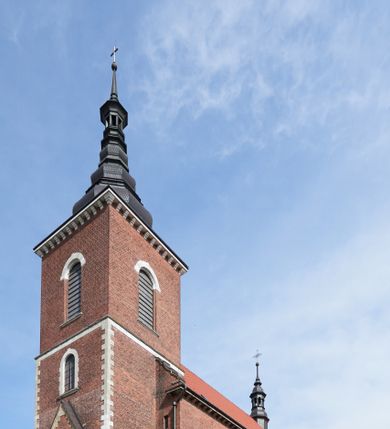 Zdjęcie nr 1: Kościół nieorientowany, skierowany prezbiterium ku północy, otoczony metalowym ogrodzeniem.  
Nawa na planie prostokąta z delikatnie wysuniętymi ramionami transeptu i z węższym oraz niższym prezbiterium, zamkniętym półkoliście, z wieżą dostawioną od fasady. Wzdłuż nawy dwuprzęsłowe arkady-kaplice, sklepione i połączone przejściami. Do wschodniego ramiona transeptu przylega kaplica Chrystusa Miłosiernego na planie prostokąta z absydą. Nawa i prezbiterium sklepione kolebkowo. Otwory okienne wysokie, zamknięte półkoliście, różnej wielkości. W prezbiterium sześć okien, w arkadach bocznych pięć, a w nawie głównej, powyżej gzymsu po sześć mniejszych na każdej ze ścian. Bryła znacznie rozczłonkowana z licznymi dobudówkami o przenikających się dachach. Nawa główna nakryta dachem dwupołaciowym, a dobudówki pulpitowymi, nałożonymi na zdwojone, wysokie okna nawy. Całą budowlę obiega gzyms podokapowy, a wokół nawy kostkowy. Wieża nakryta jest ośmiokrotnie podciętym hełmem i zwieńczona małym krzyżykiem.