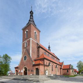 Zdjęcie nr 1: Kościół nieorientowany, skierowany prezbiterium ku północy, otoczony metalowym ogrodzeniem.  
Nawa na planie prostokąta z delikatnie wysuniętymi ramionami transeptu i z węższym oraz niższym prezbiterium, zamkniętym półkoliście, z wieżą dostawioną od fasady. Wzdłuż nawy dwuprzęsłowe arkady-kaplice, sklepione i połączone przejściami. Do wschodniego ramiona transeptu przylega kaplica Chrystusa Miłosiernego na planie prostokąta z absydą. Nawa i prezbiterium sklepione kolebkowo. Otwory okienne wysokie, zamknięte półkoliście, różnej wielkości. W prezbiterium sześć okien, w arkadach bocznych pięć, a w nawie głównej, powyżej gzymsu po sześć mniejszych na każdej ze ścian. Bryła znacznie rozczłonkowana z licznymi dobudówkami o przenikających się dachach. Nawa główna nakryta dachem dwupołaciowym, a dobudówki pulpitowymi, nałożonymi na zdwojone, wysokie okna nawy. Całą budowlę obiega gzyms podokapowy, a wokół nawy kostkowy. Wieża nakryta jest ośmiokrotnie podciętym hełmem i zwieńczona małym krzyżykiem.