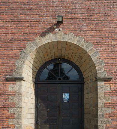 Zdjęcie nr 7: Kościół nieorientowany, skierowany prezbiterium ku północy, otoczony metalowym ogrodzeniem.  
Nawa na planie prostokąta z delikatnie wysuniętymi ramionami transeptu i z węższym oraz niższym prezbiterium, zamkniętym półkoliście, z wieżą dostawioną od fasady. Wzdłuż nawy dwuprzęsłowe arkady-kaplice, sklepione i połączone przejściami. Do wschodniego ramiona transeptu przylega kaplica Chrystusa Miłosiernego na planie prostokąta z absydą. Nawa i prezbiterium sklepione kolebkowo. Otwory okienne wysokie, zamknięte półkoliście, różnej wielkości. W prezbiterium sześć okien, w arkadach bocznych pięć, a w nawie głównej, powyżej gzymsu po sześć mniejszych na każdej ze ścian. Bryła znacznie rozczłonkowana z licznymi dobudówkami o przenikających się dachach. Nawa główna nakryta dachem dwupołaciowym, a dobudówki pulpitowymi, nałożonymi na zdwojone, wysokie okna nawy. Całą budowlę obiega gzyms podokapowy, a wokół nawy kostkowy. Wieża nakryta jest ośmiokrotnie podciętym hełmem i zwieńczona małym krzyżykiem.