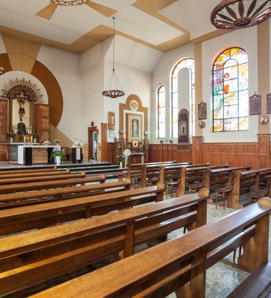 Zdjęcie nr 15: Kościół Podwyższenia Krzyża Świętego w Janowicach jest zlokalizowany na niewielkim wzniesieniu, w centrum prostokątnego placu otoczonego murowanym ogrodzeniem podzielonym na przęsła. W południowo-zachodnim narożu terenu przykościelnego usytuowana jest parawanowa dzwonnica. Kościół to budowla murowana z cegły, jednonawowa na planie krzyża łacińskiego. Do czteroprzęsłowej nawy przylega wyniesione na czterostopniowym podwyższeniu prezbiterium zamknięte prostą ścianą. Do prezbiterium od zachodu przylega zakrystia na planie zbliżonym do litery „L”, od wschodu aneks na analogicznym planie. Zakrystia skomunikowana jest z dobudowaną od południa dwukondygnacyjną i podpiwniczoną  plebanią. Wnętrze świątyni przekryte jest płaskim stropem o konstrukcji żelbetowej. Ściany w dolnej części artykułowane są za pomocą boazerii, w wyższych partiach podziały kontynuowane są w polichromii. W górnych partiach ścian (poza prezbiterium) znajdują się ukośne sufity, w nawie dodatkowo poprzedzone profilowanym gzymsem. W najwyższym rzędzie płycin mieszczą się płaskorzeźbione, stylizowane rozety z motywami geometrycznymi; analogiczne rozety zdobią parapet chóru muzycznego. Nawę doświetlają okna w kształcie stojącego prostokąta zamkniętego półkoliście: po jednym w przęsłach od drugiego do czwartego i jedno nieco większe, ponad chórem w ścianie północnej. W ścianach zamykających transept znajdują się po trzy duże otwory okienne złożone z umieszczonego po środku dużego okna w kształcie odwróconej podkowy oraz flankujących go mniejszych okien w kształcie stojącego prostokąta zamkniętego półkoliście. Główne wejście do świątyni znajduje się na osi budynku, w ścianie północnej, wejście boczne usytuowane jest w północnej ścianie zachodniego ramienia transeptu. Na szerokości pierwszego od północy przęsła nawy znajduje się chór muzyczny o konstrukcji żelbetowej, wsparty na dwóch filarach. Pod nim mieści się kruchta. Parapet chóru muzycznego jest murowany, prosty, w części środkowej trójbocznie wyłamany do wnętrza kościoła. W osi środkowej trójdzielnej fasady kościoła umieszczona wieża na planie kwadratu, nieco cofnięta w stosunku do lica elewacji, którą ujmują ukośnie ustawione ściany. Wejście do świątyni znajduje się na osi fasady. Jest zadaszone płaskim dachem; prowadzą do niego siedmiostopniowe schody. Od strony zachodniej zlokalizowany jest podjazd dla niepełnosprawnych. Otwór wejściowy ma kształt prostokąta, wewnątrz znajdują się drewniane, dwuskrzydłowe drzwi. Powyżej umiejscowione jest duże okno w kształcie stojącego prostokąta zamkniętego półkoliście. W górnej części wieży umieszczono trzy wysmukłe okna zamknięte półkoliście. W zwieńczeniu mieści się ażurowy prześwit pełniący funkcję tarasu widokowego. Wieżę wieńczy hełm w kształcie wysmukłego ostrosłupa z krzyżem. Elewacje boczne pozbawione są dekoracji.


