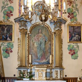 Zdjęcie nr 1: Ołtarz przyścienny, architektoniczny z murowaną mensą z kamiennym portatylem, antepedium z chrystogramem. Na mensie prostopadłościenne tabernakulum, ujęte pilastrami zwieńczonymi gzymsem, z drzwiczkami zakończonymi łukiem koszowym, na których kielich z hostią ujętą  kwiatami róż. Nastawa ołtarzowa jednokondygnacyjna, jednoosiowa ze zwieńczeniem. Retabulum ujęte parą kanelowanych filarów o korynckich głowicach, ustawionych na ukośnie dostawionych cokołach. Podpory ustawione na tle kanelowanych pilastrów wspierają ukośne odcinki belkowania zamknięte wydatnym gzymsem. Zwieńczenie o wklęsłych bokach, zamknięte łukiem nadwieszanym. 
Pole środkowe w formie prostokątnej wnęki z uskokiem u dołu, zamkniętej łukiem nadwieszonym. Wnęka ujęta ażurową ramą formowaną ze zwiniętych liści akantu, wewnątrz obraz z przedstawieniem Najświętszego Serca Jezusa. Antepedium drewniane, ujęte profilowaną ramą, pośrodku aplikowany hierogram. W zwieńczeniu medalion z rzeźbioną gołębicą Ducha świętego w promieniach. Pola cokołów zdobione płycinami ze zwiniętymi liśćmi akantu, w partii fryzu aplikowane rozety. Po bokach retabulum uszaki formowane z ornamentu kandelabrowego. Na gzymsie para rzeźbionych, uskrzydlonych aniołków. Całość struktury ołtarza malowana w odcieniach szarości, detal architektoniczny i profilowania pozłacane.
