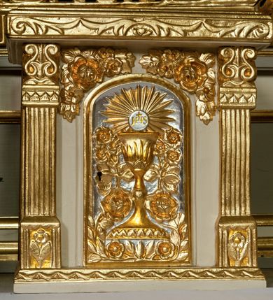 Zdjęcie nr 5: Ołtarz przyścienny, architektoniczny z murowaną mensą z kamiennym portatylem, antepedium z chrystogramem. Na mensie prostopadłościenne tabernakulum, ujęte pilastrami zwieńczonymi gzymsem, z drzwiczkami zakończonymi łukiem koszowym, na których kielich z hostią ujętą  kwiatami róż. Nastawa ołtarzowa jednokondygnacyjna, jednoosiowa ze zwieńczeniem. Retabulum ujęte parą kanelowanych filarów o korynckich głowicach, ustawionych na ukośnie dostawionych cokołach. Podpory ustawione na tle kanelowanych pilastrów wspierają ukośne odcinki belkowania zamknięte wydatnym gzymsem. Zwieńczenie o wklęsłych bokach, zamknięte łukiem nadwieszanym. 
Pole środkowe w formie prostokątnej wnęki z uskokiem u dołu, zamkniętej łukiem nadwieszonym. Wnęka ujęta ażurową ramą formowaną ze zwiniętych liści akantu, wewnątrz obraz z przedstawieniem Najświętszego Serca Jezusa. Antepedium drewniane, ujęte profilowaną ramą, pośrodku aplikowany hierogram. W zwieńczeniu medalion z rzeźbioną gołębicą Ducha świętego w promieniach. Pola cokołów zdobione płycinami ze zwiniętymi liśćmi akantu, w partii fryzu aplikowane rozety. Po bokach retabulum uszaki formowane z ornamentu kandelabrowego. Na gzymsie para rzeźbionych, uskrzydlonych aniołków. Całość struktury ołtarza malowana w odcieniach szarości, detal architektoniczny i profilowania pozłacane.
