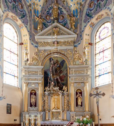 Zdjęcie nr 1: Nastawa ołtarzowa architektoniczna skomponowana na schemacie łuku triumfalnego, trójosiowa, jednokondygnacyjna ze zwieńczeniem. Ołtarz kamienny, licowany marmurowymi płytkami, z kamienną mensą. Oś środkowa jest dwukrotnie wyższa od bocznych i szersza, zamknięta półkoliście. Osie boczne ujęte dwiema parami pilastrów i stojących przed nimi kolumn o kanelowanych trzonach i kapitelach kompozytowych; między nimi nisze zwieńczone konchą z figurami św. Jana Chrzciciela i św. Jana Ewangelisty. Podpory dźwigają dwustrefowe belkowanie – niższe pełne, wyższe niepełne, delikatnie wyłamane na ich linii. Oś środkową ujmują woluty z figurami aniołów spływające na belkowanie osi bocznych; na skraju postumenty z figurami św. Floriana i św. Wacława(?). Postumenty kolumn dekorowane z trzech stron płycinami, od frontu z uskrzydlonymi główkami anielskimi; pomiędzy nimi rollwerki  z podpisami figur. Podłucze osi środkowej dekorowane kasetonami z rozetami; archiwolta wypełniona akantem, zwieńczona kluczem; w przyłuczach dwie płaskorzeźbione figury kobiece. Powyżej fryz dekorowany dużych rozmiarów uskrzydloną głową anielską, ujętą wicią roślinną, na gzymsie kartusz. W polu przyczółka roślinny postument podtrzymujący dwie uskrzydlone główki anielskie. W przyłuczach konch osi bocznych ornament roślinny, powyżej rauty, u spodu figur festony. Spód belkowania dekorowany kasetonami z rozetami. Fryzy dwóch stref belkowania wypełnione ornamentem roślinnym i rozetami; na wewnętrznym boku drugiej strefy para herbów Radwan. W polu środkowym obraz ukazujący Zwiastowanie Najświętszej Marii Panny, a na zasuwie Św. Michała Archanioła. Struktura polichromowana na szaro; kolumny, ornamentyka i profile złocone.
