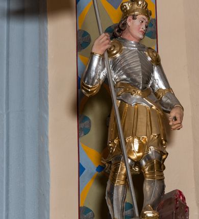 Zdjęcie nr 16: Nastawa ołtarzowa architektoniczna skomponowana na schemacie łuku triumfalnego, trójosiowa, jednokondygnacyjna ze zwieńczeniem. Ołtarz kamienny, licowany marmurowymi płytkami, z kamienną mensą. Oś środkowa jest dwukrotnie wyższa od bocznych i szersza, zamknięta półkoliście. Osie boczne ujęte dwiema parami pilastrów i stojących przed nimi kolumn o kanelowanych trzonach i kapitelach kompozytowych; między nimi nisze zwieńczone konchą z figurami św. Jana Chrzciciela i św. Jana Ewangelisty. Podpory dźwigają dwustrefowe belkowanie – niższe pełne, wyższe niepełne, delikatnie wyłamane na ich linii. Oś środkową ujmują woluty z figurami aniołów spływające na belkowanie osi bocznych; na skraju postumenty z figurami św. Floriana i św. Wacława(?). Postumenty kolumn dekorowane z trzech stron płycinami, od frontu z uskrzydlonymi główkami anielskimi; pomiędzy nimi rollwerki  z podpisami figur. Podłucze osi środkowej dekorowane kasetonami z rozetami; archiwolta wypełniona akantem, zwieńczona kluczem; w przyłuczach dwie płaskorzeźbione figury kobiece. Powyżej fryz dekorowany dużych rozmiarów uskrzydloną głową anielską, ujętą wicią roślinną, na gzymsie kartusz. W polu przyczółka roślinny postument podtrzymujący dwie uskrzydlone główki anielskie. W przyłuczach konch osi bocznych ornament roślinny, powyżej rauty, u spodu figur festony. Spód belkowania dekorowany kasetonami z rozetami. Fryzy dwóch stref belkowania wypełnione ornamentem roślinnym i rozetami; na wewnętrznym boku drugiej strefy para herbów Radwan. W polu środkowym obraz ukazujący Zwiastowanie Najświętszej Marii Panny, a na zasuwie Św. Michała Archanioła. Struktura polichromowana na szaro; kolumny, ornamentyka i profile złocone.
