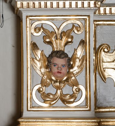 Zdjęcie nr 34: Nastawa ołtarzowa architektoniczna skomponowana na schemacie łuku triumfalnego, trójosiowa, jednokondygnacyjna ze zwieńczeniem. Ołtarz kamienny, licowany marmurowymi płytkami, z kamienną mensą. Oś środkowa jest dwukrotnie wyższa od bocznych i szersza, zamknięta półkoliście. Osie boczne ujęte dwiema parami pilastrów i stojących przed nimi kolumn o kanelowanych trzonach i kapitelach kompozytowych; między nimi nisze zwieńczone konchą z figurami św. Jana Chrzciciela i św. Jana Ewangelisty. Podpory dźwigają dwustrefowe belkowanie – niższe pełne, wyższe niepełne, delikatnie wyłamane na ich linii. Oś środkową ujmują woluty z figurami aniołów spływające na belkowanie osi bocznych; na skraju postumenty z figurami św. Floriana i św. Wacława(?). Postumenty kolumn dekorowane z trzech stron płycinami, od frontu z uskrzydlonymi główkami anielskimi; pomiędzy nimi rollwerki  z podpisami figur. Podłucze osi środkowej dekorowane kasetonami z rozetami; archiwolta wypełniona akantem, zwieńczona kluczem; w przyłuczach dwie płaskorzeźbione figury kobiece. Powyżej fryz dekorowany dużych rozmiarów uskrzydloną głową anielską, ujętą wicią roślinną, na gzymsie kartusz. W polu przyczółka roślinny postument podtrzymujący dwie uskrzydlone główki anielskie. W przyłuczach konch osi bocznych ornament roślinny, powyżej rauty, u spodu figur festony. Spód belkowania dekorowany kasetonami z rozetami. Fryzy dwóch stref belkowania wypełnione ornamentem roślinnym i rozetami; na wewnętrznym boku drugiej strefy para herbów Radwan. W polu środkowym obraz ukazujący Zwiastowanie Najświętszej Marii Panny, a na zasuwie Św. Michała Archanioła. Struktura polichromowana na szaro; kolumny, ornamentyka i profile złocone.
