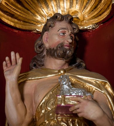 Zdjęcie nr 9: Nastawa ołtarzowa architektoniczna skomponowana na schemacie łuku triumfalnego, trójosiowa, jednokondygnacyjna ze zwieńczeniem. Ołtarz kamienny, licowany marmurowymi płytkami, z kamienną mensą. Oś środkowa jest dwukrotnie wyższa od bocznych i szersza, zamknięta półkoliście. Osie boczne ujęte dwiema parami pilastrów i stojących przed nimi kolumn o kanelowanych trzonach i kapitelach kompozytowych; między nimi nisze zwieńczone konchą z figurami św. Jana Chrzciciela i św. Jana Ewangelisty. Podpory dźwigają dwustrefowe belkowanie – niższe pełne, wyższe niepełne, delikatnie wyłamane na ich linii. Oś środkową ujmują woluty z figurami aniołów spływające na belkowanie osi bocznych; na skraju postumenty z figurami św. Floriana i św. Wacława(?). Postumenty kolumn dekorowane z trzech stron płycinami, od frontu z uskrzydlonymi główkami anielskimi; pomiędzy nimi rollwerki  z podpisami figur. Podłucze osi środkowej dekorowane kasetonami z rozetami; archiwolta wypełniona akantem, zwieńczona kluczem; w przyłuczach dwie płaskorzeźbione figury kobiece. Powyżej fryz dekorowany dużych rozmiarów uskrzydloną głową anielską, ujętą wicią roślinną, na gzymsie kartusz. W polu przyczółka roślinny postument podtrzymujący dwie uskrzydlone główki anielskie. W przyłuczach konch osi bocznych ornament roślinny, powyżej rauty, u spodu figur festony. Spód belkowania dekorowany kasetonami z rozetami. Fryzy dwóch stref belkowania wypełnione ornamentem roślinnym i rozetami; na wewnętrznym boku drugiej strefy para herbów Radwan. W polu środkowym obraz ukazujący Zwiastowanie Najświętszej Marii Panny, a na zasuwie Św. Michała Archanioła. Struktura polichromowana na szaro; kolumny, ornamentyka i profile złocone.
