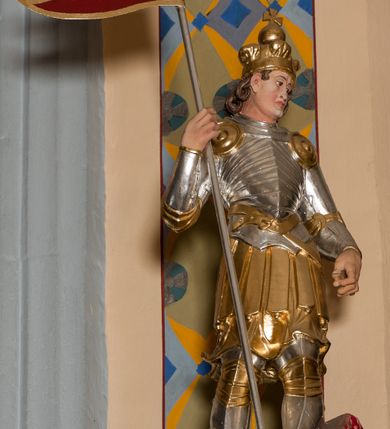 Zdjęcie nr 45: Nastawa ołtarzowa architektoniczna skomponowana na schemacie łuku triumfalnego, trójosiowa, jednokondygnacyjna ze zwieńczeniem. Ołtarz kamienny, licowany marmurowymi płytkami, z kamienną mensą. Oś środkowa jest dwukrotnie wyższa od bocznych i szersza, zamknięta półkoliście. Osie boczne ujęte dwiema parami pilastrów i stojących przed nimi kolumn o kanelowanych trzonach i kapitelach kompozytowych; między nimi nisze zwieńczone konchą z figurami św. Jana Chrzciciela i św. Jana Ewangelisty. Podpory dźwigają dwustrefowe belkowanie – niższe pełne, wyższe niepełne, delikatnie wyłamane na ich linii. Oś środkową ujmują woluty z figurami aniołów spływające na belkowanie osi bocznych; na skraju postumenty z figurami św. Floriana i św. Wacława(?). Postumenty kolumn dekorowane z trzech stron płycinami, od frontu z uskrzydlonymi główkami anielskimi; pomiędzy nimi rollwerki  z podpisami figur. Podłucze osi środkowej dekorowane kasetonami z rozetami; archiwolta wypełniona akantem, zwieńczona kluczem; w przyłuczach dwie płaskorzeźbione figury kobiece. Powyżej fryz dekorowany dużych rozmiarów uskrzydloną głową anielską, ujętą wicią roślinną, na gzymsie kartusz. W polu przyczółka roślinny postument podtrzymujący dwie uskrzydlone główki anielskie. W przyłuczach konch osi bocznych ornament roślinny, powyżej rauty, u spodu figur festony. Spód belkowania dekorowany kasetonami z rozetami. Fryzy dwóch stref belkowania wypełnione ornamentem roślinnym i rozetami; na wewnętrznym boku drugiej strefy para herbów Radwan. W polu środkowym obraz ukazujący Zwiastowanie Najświętszej Marii Panny, a na zasuwie Św. Michała Archanioła. Struktura polichromowana na szaro; kolumny, ornamentyka i profile złocone.
