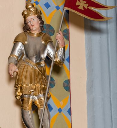 Zdjęcie nr 52: Nastawa ołtarzowa architektoniczna skomponowana na schemacie łuku triumfalnego, trójosiowa, jednokondygnacyjna ze zwieńczeniem. Ołtarz kamienny, licowany marmurowymi płytkami, z kamienną mensą. Oś środkowa jest dwukrotnie wyższa od bocznych i szersza, zamknięta półkoliście. Osie boczne ujęte dwiema parami pilastrów i stojących przed nimi kolumn o kanelowanych trzonach i kapitelach kompozytowych; między nimi nisze zwieńczone konchą z figurami św. Jana Chrzciciela i św. Jana Ewangelisty. Podpory dźwigają dwustrefowe belkowanie – niższe pełne, wyższe niepełne, delikatnie wyłamane na ich linii. Oś środkową ujmują woluty z figurami aniołów spływające na belkowanie osi bocznych; na skraju postumenty z figurami św. Floriana i św. Wacława(?). Postumenty kolumn dekorowane z trzech stron płycinami, od frontu z uskrzydlonymi główkami anielskimi; pomiędzy nimi rollwerki  z podpisami figur. Podłucze osi środkowej dekorowane kasetonami z rozetami; archiwolta wypełniona akantem, zwieńczona kluczem; w przyłuczach dwie płaskorzeźbione figury kobiece. Powyżej fryz dekorowany dużych rozmiarów uskrzydloną głową anielską, ujętą wicią roślinną, na gzymsie kartusz. W polu przyczółka roślinny postument podtrzymujący dwie uskrzydlone główki anielskie. W przyłuczach konch osi bocznych ornament roślinny, powyżej rauty, u spodu figur festony. Spód belkowania dekorowany kasetonami z rozetami. Fryzy dwóch stref belkowania wypełnione ornamentem roślinnym i rozetami; na wewnętrznym boku drugiej strefy para herbów Radwan. W polu środkowym obraz ukazujący Zwiastowanie Najświętszej Marii Panny, a na zasuwie Św. Michała Archanioła. Struktura polichromowana na szaro; kolumny, ornamentyka i profile złocone.
