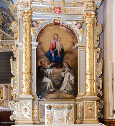 Zdjęcie nr 1: Ołtarz architektoniczny, jednoosiowy, jednokondygnacyjny ze zwieńczeniem. Antepedium z prostokątną ramą o ćwierćkoliście wyciętych narożach z promienimi i monogramem MARIA. Na mensie prostopadłościenne tabernakulum z drzwiczkami wypełnionymi płaskorzeźbionym barankiem apokaliptycznym. Wokół drzwiczek winna latorośl a w narożach uskrzydlone główki aniołków. Kompozycja nastawy wykorzystuje schemat łuku triumfalnego z arkadą zamknietą półkoliście flankowaną kolumnami stojącymi na postumentach, z kompozytowymi kapitelami dźwigającymi belkowanie. Nad belkowaniem przerwany i wyłamujący się ponad kolumnami, segmentowy przyczółek. W arkadzie obraz z Matką Boską Różąńcową ze św. Katarzyną Sieneńską i św. Dominikiem. Na zwieńczeniu dwie siedzące figury Ewangelistów (?), brodatych, ubranych w długie suknie i płaszcze, z otwartą księgą i piórem w dłoniach. W partii przerwanego przyczółka stoi na postumencie anioł z rozwartymi rękami, ubrany w długą suknię, z rozpostartymi skrzydłami. 
Cokoły zdobią motywy okuciowe z główkami aniołów. Kolumny w jednej trzeciej ujęte profilowaniem, w dolnej pokryte są okuciowymi taśmami i główkami aniołków, a w górnej wijącą się spiralnie wicią roślinną. Boki nastawy ujmują uszy utworzone z zawijających się taśm. Nad niszą z obrazem główki aniołków. Profile belkowania ozdobione konsolkami i kostkowaniem a fryz wicią roślinną i medalionem z literami IHS. Podobne ornamenty w partii przyczółka. Kolorystyka ołtarza jest szara, kolumny, profile, złocone i srebrzone, twarze aniołków i postaci w zwieńczeniu polichromowane naturalistycznie.  
