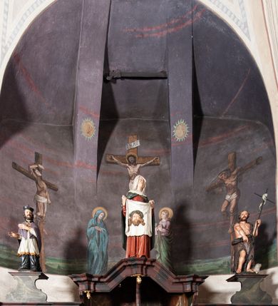 Zdjęcie nr 3: Konfesjonał do słuchania spowiedzi usznej, dwuosobowy, prostopadłościenny, od przodu z parą drzwiczek osadzonych na zawiasach, zwieńczony gzymsem pośrodku wyłamanym trójbocznie. Drzwiczki konfesjonału przedzielone kolumienką, zdobione prostokątnymi płycinami zamkniętymi łukiem półpełnym nadwieszonym. Wewnątrz siedziska oddzielone pionową ścianką o dekoracyjnym wykroju. Płyciny i tylna ściana wnętrza marmoryzowane. Po bokach dwie ścianki parawanowe z prostokątnymi zamkniętymi łukiem kotarowym bramkami dla penitentów. Bramki ujęte pilastrami o kapitelach w formie główki aniołka ze złoconymi skrzydełkami, dźwigającymi uproszczone belkowanie i gzyms występujący nad podporami. W przyłuczach bramek dekoracja malarska. Na gzymsie ustawione rzeźby pełnoplastyczne, polichromowane: w osi środkowej święta Weronika z chustą, w osiach bramek na konsolach o ozdobnym wykroju święty Jan Nepomucen (po lewej) i święty Jan Chrzciciel po prawej. 