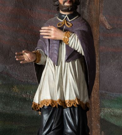 Zdjęcie nr 2: Konfesjonał do słuchania spowiedzi usznej, dwuosobowy, prostopadłościenny, od przodu z parą drzwiczek osadzonych na zawiasach, zwieńczony gzymsem pośrodku wyłamanym trójbocznie. Drzwiczki konfesjonału przedzielone kolumienką, zdobione prostokątnymi płycinami zamkniętymi łukiem półpełnym nadwieszonym. Wewnątrz siedziska oddzielone pionową ścianką o dekoracyjnym wykroju. Płyciny i tylna ściana wnętrza marmoryzowane. Po bokach dwie ścianki parawanowe z prostokątnymi zamkniętymi łukiem kotarowym bramkami dla penitentów. Bramki ujęte pilastrami o kapitelach w formie główki aniołka ze złoconymi skrzydełkami, dźwigającymi uproszczone belkowanie i gzyms występujący nad podporami. W przyłuczach bramek dekoracja malarska. Na gzymsie ustawione rzeźby pełnoplastyczne, polichromowane: w osi środkowej święta Weronika z chustą, w osiach bramek na konsolach o ozdobnym wykroju święty Jan Nepomucen (po lewej) i święty Jan Chrzciciel po prawej. 