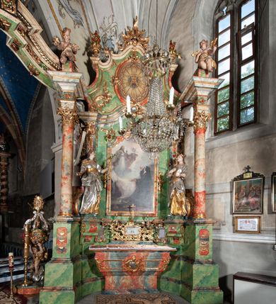 Zdjęcie nr 2: Ołtarz na rzucie połowy owalu, architektoniczny, kulisowy, jednokondygnacyjny, jednoosiowy, ze zwieńczeniem. Drewniana mensa ołtarza (późniejsza) oparta na skrzyni o formie tumby z wydzielonym cokołem. Retabulum na wysokim potrójnym, cokole, ujęte parą ukośnie ustawionych konsol o formie wolut, na których ustawione rzeźby, oraz parą odsuniętych od lica części środkowej kolumn o gładkich trzonach i kompozytowych kapitelach, wspierających przerwane belkowanie i gzyms. Pole środkowe ujęte pilastrami o wolutowych kapitelach, zwieńczone gzymsem wygiętym łukiem wklęsło-wypukłym. Pośrodku pola profilowana rama zamknięta łukiem wklęsło-wypukłym nadwieszonym, na obraz ołtarzowy. Zwieńczenie o dekoracyjnym wykroju linią wklęsło-wypukłą, z wysuniętymi na kolumny spływami wolutowymi.  Pośrodku zwieńczenia profilowana rama w kształcie stojącego owalu. Antepedium, część środkowa retabulum oraz zwieńczenie zdobione motywami ornamentów rokokowych. Retabulum ujęte parą ażurowych, rokokowych uszaków. W płycinach na spływach motywy roślinne i rozetki. Pośrodku gzymsu wieńczącego część środkową retabulum kartusz ujęty ornamentem rokokowym. W zwieńczeniu, na gzymsie, po bokach para wazonów z kwiatami, szczyt z dekoracją roccaillową. W polu środkowym obraz Objawienie się Chrystusa św. Małgorzacie Alacoque. Na wolutowych konsolach po bokach rzeźby św. Apolonii po lewej i św. Rozalii z Palermo po prawej stronie. W zwieńczeniu malowane ozdobne litery IHS z krzyżem, ujęte promienistą glorią oraz koroną cierniową. W osiach kolumn na spływach wolutowych zwieńczenia para aniołków. Na mensie trzy kanony ołtarzowe ujęte ażurowymi ramami ze stylizowanych wici akantu, zdobione rozetami. Struktura ołtarza w całości marmoryzowana, kolorystyka w odcieniach zieleni, beżów, czerwieni i niebieskim. Fragmenty detalu architektonicznego i ornamenty złocone i srebrzone. 