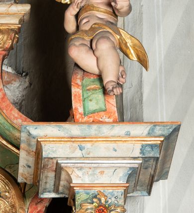 Zdjęcie nr 18: Ołtarz na rzucie połowy owalu, architektoniczny, kulisowy, jednokondygnacyjny, jednoosiowy, ze zwieńczeniem. Drewniana mensa ołtarza (późniejsza) oparta na skrzyni o formie tumby z wydzielonym cokołem. Retabulum na wysokim potrójnym, cokole, ujęte parą ukośnie ustawionych konsol o formie wolut, na których ustawione rzeźby, oraz parą odsuniętych od lica części środkowej kolumn o gładkich trzonach i kompozytowych kapitelach, wspierających przerwane belkowanie i gzyms. Pole środkowe ujęte pilastrami o wolutowych kapitelach, zwieńczone gzymsem wygiętym łukiem wklęsło-wypukłym. Pośrodku pola profilowana rama zamknięta łukiem wklęsło-wypukłym nadwieszonym, na obraz ołtarzowy. Zwieńczenie o dekoracyjnym wykroju linią wklęsło-wypukłą, z wysuniętymi na kolumny spływami wolutowymi.  Pośrodku zwieńczenia profilowana rama w kształcie stojącego owalu. Antepedium, część środkowa retabulum oraz zwieńczenie zdobione motywami ornamentów rokokowych. Retabulum ujęte parą ażurowych, rokokowych uszaków. W płycinach na spływach motywy roślinne i rozetki. Pośrodku gzymsu wieńczącego część środkową retabulum kartusz ujęty ornamentem rokokowym. W zwieńczeniu, na gzymsie, po bokach para wazonów z kwiatami, szczyt z dekoracją roccaillową. W polu środkowym obraz Objawienie się Chrystusa św. Małgorzacie Alacoque. Na wolutowych konsolach po bokach rzeźby św. Apolonii po lewej i św. Rozalii z Palermo po prawej stronie. W zwieńczeniu malowane ozdobne litery IHS z krzyżem, ujęte promienistą glorią oraz koroną cierniową. W osiach kolumn na spływach wolutowych zwieńczenia para aniołków. Na mensie trzy kanony ołtarzowe ujęte ażurowymi ramami ze stylizowanych wici akantu, zdobione rozetami. Struktura ołtarza w całości marmoryzowana, kolorystyka w odcieniach zieleni, beżów, czerwieni i niebieskim. Fragmenty detalu architektonicznego i ornamenty złocone i srebrzone. 