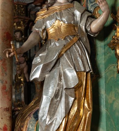 Zdjęcie nr 11: Ołtarz na rzucie połowy owalu, architektoniczny, kulisowy, jednokondygnacyjny, jednoosiowy, ze zwieńczeniem. Drewniana mensa ołtarza (późniejsza) oparta na skrzyni o formie tumby z wydzielonym cokołem. Retabulum na wysokim potrójnym, cokole, ujęte parą ukośnie ustawionych konsol o formie wolut, na których ustawione rzeźby, oraz parą odsuniętych od lica części środkowej kolumn o gładkich trzonach i kompozytowych kapitelach, wspierających przerwane belkowanie i gzyms. Pole środkowe ujęte pilastrami o wolutowych kapitelach, zwieńczone gzymsem wygiętym łukiem wklęsło-wypukłym. Pośrodku pola profilowana rama zamknięta łukiem wklęsło-wypukłym nadwieszonym, na obraz ołtarzowy. Zwieńczenie o dekoracyjnym wykroju linią wklęsło-wypukłą, z wysuniętymi na kolumny spływami wolutowymi.  Pośrodku zwieńczenia profilowana rama w kształcie stojącego owalu. Antepedium, część środkowa retabulum oraz zwieńczenie zdobione motywami ornamentów rokokowych. Retabulum ujęte parą ażurowych, rokokowych uszaków. W płycinach na spływach motywy roślinne i rozetki. Pośrodku gzymsu wieńczącego część środkową retabulum kartusz ujęty ornamentem rokokowym. W zwieńczeniu, na gzymsie, po bokach para wazonów z kwiatami, szczyt z dekoracją roccaillową. W polu środkowym obraz Objawienie się Chrystusa św. Małgorzacie Alacoque. Na wolutowych konsolach po bokach rzeźby św. Apolonii po lewej i św. Rozalii z Palermo po prawej stronie. W zwieńczeniu malowane ozdobne litery IHS z krzyżem, ujęte promienistą glorią oraz koroną cierniową. W osiach kolumn na spływach wolutowych zwieńczenia para aniołków. Na mensie trzy kanony ołtarzowe ujęte ażurowymi ramami ze stylizowanych wici akantu, zdobione rozetami. Struktura ołtarza w całości marmoryzowana, kolorystyka w odcieniach zieleni, beżów, czerwieni i niebieskim. Fragmenty detalu architektonicznego i ornamenty złocone i srebrzone. 