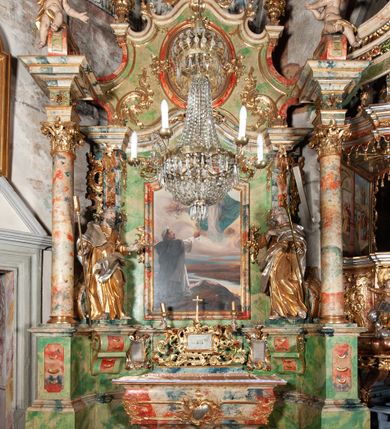 Zdjęcie nr 3: Ołtarz na rzucie połowy owalu, architektoniczny, kulisowy, jednokondygnacyjny, jednoosiowy, ze zwieńczeniem. Drewniana mensa ołtarza (późniejsza) oparta na skrzyni o formie tumby z wydzielonym cokołem. Retabulum na wysokim potrójnym, cokole, ujęte parą ukośnie ustawionych konsol o formie wolut, na których ustawione rzeźby, oraz parą odsuniętych od lica części środkowej kolumn o gładkich trzonach i kompozytowych kapitelach, wspierających przerwane belkowanie i gzyms. Pole środkowe ujęte pilastrami o wolutowych kapitelach, zwieńczone gzymsem wygiętym łukiem wklęsło-wypukłym. Pośrodku pola profilowana rama zamknięta łukiem wklęsło-wypukłym nadwieszonym, na obraz ołtarzowy. Zwieńczenie o dekoracyjnym wykroju linią wklęsło-wypukłą, z  wysuniętymi  na kolumny spływami wolutowymi.  Pośrodku zwieńczenia profilowana rama w kształcie stojącego owalu. Antepedium, część środkowa retabulum oraz zwieńczenie zdobione motywami ornamentów rokokowych. Retabulum ujęte parą ażurowych, rokokowych uszaków. W płycinach na spływach motywy roślinne i rozetki. Pośrodku gzymsu wieńczącego część środkową retabulum kartusz ujęty ornamentem rokokowym. W zwieńczeniu, na gzymsie, po bokach para wazonów z kwiatami, szczyt z dekoracją roccaillową. W polu środkowym obraz Matka Boska Różańcowa ze świętym Dominikiem. Na wolutowych konsolach po bokach rzeźby św. Joachima po lewej i św. Józefa po prawej stronie. W zwieńczeniu malowane splecione litery imienia MARIA, ujęte promienistą glorią oraz wieńcem z róż. W osiach kolumn na spływach wolutowych zwieńczenia para aniołków. Na mensie trzy kanony ołtarzowe ujęte ażurowymi ramami ze stylizowanych wici akantu, zdobione rozetami. Struktura ołtarza w całości marmoryzowana, kolorystyka w odcieniach zieleni, beżów, czerwieni i niebieskim. Fragmenty detalu architektonicznego i ornamenty złocone i srebrzone. 