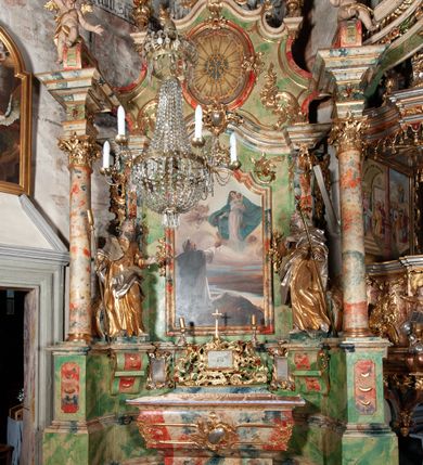 Zdjęcie nr 2: Ołtarz na rzucie połowy owalu, architektoniczny, kulisowy, jednokondygnacyjny, jednoosiowy, ze zwieńczeniem. Drewniana mensa ołtarza (późniejsza) oparta na skrzyni o formie tumby z wydzielonym cokołem. Retabulum na wysokim potrójnym, cokole, ujęte parą ukośnie ustawionych konsol o formie wolut, na których ustawione rzeźby, oraz parą odsuniętych od lica części środkowej kolumn o gładkich trzonach i kompozytowych kapitelach, wspierających przerwane belkowanie i gzyms. Pole środkowe ujęte pilastrami o wolutowych kapitelach, zwieńczone gzymsem wygiętym łukiem wklęsło-wypukłym. Pośrodku pola profilowana rama zamknięta łukiem wklęsło-wypukłym nadwieszonym, na obraz ołtarzowy. Zwieńczenie o dekoracyjnym wykroju linią wklęsło-wypukłą, z  wysuniętymi  na kolumny spływami wolutowymi.  Pośrodku zwieńczenia profilowana rama w kształcie stojącego owalu. Antepedium, część środkowa retabulum oraz zwieńczenie zdobione motywami ornamentów rokokowych. Retabulum ujęte parą ażurowych, rokokowych uszaków. W płycinach na spływach motywy roślinne i rozetki. Pośrodku gzymsu wieńczącego część środkową retabulum kartusz ujęty ornamentem rokokowym. W zwieńczeniu, na gzymsie, po bokach para wazonów z kwiatami, szczyt z dekoracją roccaillową. W polu środkowym obraz Matka Boska Różańcowa ze świętym Dominikiem. Na wolutowych konsolach po bokach rzeźby św. Joachima po lewej i św. Józefa po prawej stronie. W zwieńczeniu malowane splecione litery imienia MARIA, ujęte promienistą glorią oraz wieńcem z róż. W osiach kolumn na spływach wolutowych zwieńczenia para aniołków. Na mensie trzy kanony ołtarzowe ujęte ażurowymi ramami ze stylizowanych wici akantu, zdobione rozetami. Struktura ołtarza w całości marmoryzowana, kolorystyka w odcieniach zieleni, beżów, czerwieni i niebieskim. Fragmenty detalu architektonicznego i ornamenty złocone i srebrzone. 