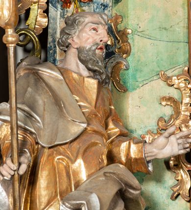 Zdjęcie nr 13: Ołtarz na rzucie połowy owalu, architektoniczny, kulisowy, jednokondygnacyjny, jednoosiowy, ze zwieńczeniem. Drewniana mensa ołtarza (późniejsza) oparta na skrzyni o formie tumby z wydzielonym cokołem. Retabulum na wysokim potrójnym, cokole, ujęte parą ukośnie ustawionych konsol o formie wolut, na których ustawione rzeźby, oraz parą odsuniętych od lica części środkowej kolumn o gładkich trzonach i kompozytowych kapitelach, wspierających przerwane belkowanie i gzyms. Pole środkowe ujęte pilastrami o wolutowych kapitelach, zwieńczone gzymsem wygiętym łukiem wklęsło-wypukłym. Pośrodku pola profilowana rama zamknięta łukiem wklęsło-wypukłym nadwieszonym, na obraz ołtarzowy. Zwieńczenie o dekoracyjnym wykroju linią wklęsło-wypukłą, z  wysuniętymi  na kolumny spływami wolutowymi.  Pośrodku zwieńczenia profilowana rama w kształcie stojącego owalu. Antepedium, część środkowa retabulum oraz zwieńczenie zdobione motywami ornamentów rokokowych. Retabulum ujęte parą ażurowych, rokokowych uszaków. W płycinach na spływach motywy roślinne i rozetki. Pośrodku gzymsu wieńczącego część środkową retabulum kartusz ujęty ornamentem rokokowym. W zwieńczeniu, na gzymsie, po bokach para wazonów z kwiatami, szczyt z dekoracją roccaillową. W polu środkowym obraz Matka Boska Różańcowa ze świętym Dominikiem. Na wolutowych konsolach po bokach rzeźby św. Joachima po lewej i św. Józefa po prawej stronie. W zwieńczeniu malowane splecione litery imienia MARIA, ujęte promienistą glorią oraz wieńcem z róż. W osiach kolumn na spływach wolutowych zwieńczenia para aniołków. Na mensie trzy kanony ołtarzowe ujęte ażurowymi ramami ze stylizowanych wici akantu, zdobione rozetami. Struktura ołtarza w całości marmoryzowana, kolorystyka w odcieniach zieleni, beżów, czerwieni i niebieskim. Fragmenty detalu architektonicznego i ornamenty złocone i srebrzone. 