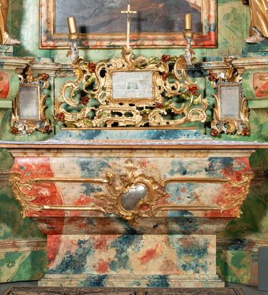 Zdjęcie nr 17: Ołtarz na rzucie połowy owalu, architektoniczny, kulisowy, jednokondygnacyjny, jednoosiowy, ze zwieńczeniem. Drewniana mensa ołtarza (późniejsza) oparta na skrzyni o formie tumby z wydzielonym cokołem. Retabulum na wysokim potrójnym, cokole, ujęte parą ukośnie ustawionych konsol o formie wolut, na których ustawione rzeźby, oraz parą odsuniętych od lica części środkowej kolumn o gładkich trzonach i kompozytowych kapitelach, wspierających przerwane belkowanie i gzyms. Pole środkowe ujęte pilastrami o wolutowych kapitelach, zwieńczone gzymsem wygiętym łukiem wklęsło-wypukłym. Pośrodku pola profilowana rama zamknięta łukiem wklęsło-wypukłym nadwieszonym, na obraz ołtarzowy. Zwieńczenie o dekoracyjnym wykroju linią wklęsło-wypukłą, z  wysuniętymi  na kolumny spływami wolutowymi.  Pośrodku zwieńczenia profilowana rama w kształcie stojącego owalu. Antepedium, część środkowa retabulum oraz zwieńczenie zdobione motywami ornamentów rokokowych. Retabulum ujęte parą ażurowych, rokokowych uszaków. W płycinach na spływach motywy roślinne i rozetki. Pośrodku gzymsu wieńczącego część środkową retabulum kartusz ujęty ornamentem rokokowym. W zwieńczeniu, na gzymsie, po bokach para wazonów z kwiatami, szczyt z dekoracją roccaillową. W polu środkowym obraz Matka Boska Różańcowa ze świętym Dominikiem. Na wolutowych konsolach po bokach rzeźby św. Joachima po lewej i św. Józefa po prawej stronie. W zwieńczeniu malowane splecione litery imienia MARIA, ujęte promienistą glorią oraz wieńcem z róż. W osiach kolumn na spływach wolutowych zwieńczenia para aniołków. Na mensie trzy kanony ołtarzowe ujęte ażurowymi ramami ze stylizowanych wici akantu, zdobione rozetami. Struktura ołtarza w całości marmoryzowana, kolorystyka w odcieniach zieleni, beżów, czerwieni i niebieskim. Fragmenty detalu architektonicznego i ornamenty złocone i srebrzone. 