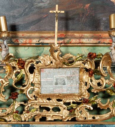 Zdjęcie nr 18: Ołtarz na rzucie połowy owalu, architektoniczny, kulisowy, jednokondygnacyjny, jednoosiowy, ze zwieńczeniem. Drewniana mensa ołtarza (późniejsza) oparta na skrzyni o formie tumby z wydzielonym cokołem. Retabulum na wysokim potrójnym, cokole, ujęte parą ukośnie ustawionych konsol o formie wolut, na których ustawione rzeźby, oraz parą odsuniętych od lica części środkowej kolumn o gładkich trzonach i kompozytowych kapitelach, wspierających przerwane belkowanie i gzyms. Pole środkowe ujęte pilastrami o wolutowych kapitelach, zwieńczone gzymsem wygiętym łukiem wklęsło-wypukłym. Pośrodku pola profilowana rama zamknięta łukiem wklęsło-wypukłym nadwieszonym, na obraz ołtarzowy. Zwieńczenie o dekoracyjnym wykroju linią wklęsło-wypukłą, z  wysuniętymi  na kolumny spływami wolutowymi.  Pośrodku zwieńczenia profilowana rama w kształcie stojącego owalu. Antepedium, część środkowa retabulum oraz zwieńczenie zdobione motywami ornamentów rokokowych. Retabulum ujęte parą ażurowych, rokokowych uszaków. W płycinach na spływach motywy roślinne i rozetki. Pośrodku gzymsu wieńczącego część środkową retabulum kartusz ujęty ornamentem rokokowym. W zwieńczeniu, na gzymsie, po bokach para wazonów z kwiatami, szczyt z dekoracją roccaillową. W polu środkowym obraz Matka Boska Różańcowa ze świętym Dominikiem. Na wolutowych konsolach po bokach rzeźby św. Joachima po lewej i św. Józefa po prawej stronie. W zwieńczeniu malowane splecione litery imienia MARIA, ujęte promienistą glorią oraz wieńcem z róż. W osiach kolumn na spływach wolutowych zwieńczenia para aniołków. Na mensie trzy kanony ołtarzowe ujęte ażurowymi ramami ze stylizowanych wici akantu, zdobione rozetami. Struktura ołtarza w całości marmoryzowana, kolorystyka w odcieniach zieleni, beżów, czerwieni i niebieskim. Fragmenty detalu architektonicznego i ornamenty złocone i srebrzone. 