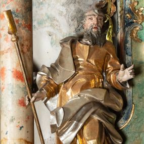 Zdjęcie nr 1: Rzeźba pełnoplastyczna, drążona od tyłu, umieszczona po lewej stronie ołtarza bocznego, przedstawiająca stojącego na niewysokim, prostopadłościennym, marmoryzowanym postumencie św. Joachima. Święty ukazany frontalnie, w kontrapoście. Głowa lekko przechylona w prawo, włosy falowane, krótkie, siwe. Twarz o wyrazistych rysach i długim siwym zaroście. Oczy zwrócone lekko ku górze, usta rozchylone. Lewa ręka świętego, zgięta w łokciu, uniesiona na wysokości talii, prawą podtrzymuje laskę pasterską. Święty ubrany w długą, złoconą tunikę i narzucony na nią srebrzony płaszcz. Fałdy szat układają się równolegle, miejscami spłaszczone, miejscami załamujące się. Spod tuniki widoczne bose stopy. 