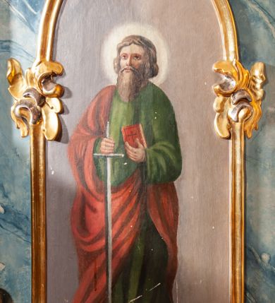 Zdjęcie nr 30: Ołtarz architektoniczny, trójosiowy, z wydzieloną częścią cokołową, jednokondygnacyjny, ze zwieńczeniem. Mensa drewniana tumbowa, ozdobiona nałożonymi płaskorzeźbionymi motywami rocaille’ów i roślinnymi. Po bokach mensy, w części cokołowej dwie bramki obejścia zamknięte półkoliście, w których osadzone na zawiasach drzwi jednoskrzydłowe z płycinami z malowanymi przedstawieniami świętych. W predelli oszklona trumienka z rzeźbą Chrystusa w grobie. Pole środkowe nastawy ujęte dwoma czworobocznymi filarami o kompozytowych kapitelach. Pola boczne wklęsłe i cofnięte od lica pola środkowego flankowane kolumnami o gładkich trzonach i kompozytowych kapitelach, umieszczonych na wysokich dwustopniowych postumentach ustawionych kątowo, zdobionych płycinami. Podpory dźwigają pełne belkowanie i gzyms, przerwane nad polem środkowym. W polu środkowym głęboka nisza w kształcie prostokąta stojącego zamkniętego łukiem wypukło-wklęsłym, w bogatym obramieniu. W niej rzeźba Pieta. Po bokach, na tle filarów, umieszczone dwa okazałe anioły w dynamicznych pozach, z rozłożonymi skrzydłami. Ponad niszą płaskorzeźbiona Chusta św. Weroniki rozpostarta przez dwa uskrzydlone putta ze stopami wspartymi na obłokach. W polach bocznych nastawy sferyczne płyciny w asymetrycznych złoconych obramieniach, na których tle umieszczone na konsolach rzeźby: Św. Jan Ewangelista (po lewej) i Św. Maria Magdalena (po prawej). Zwieńczenie w formie aedikuli ujętej wolutami i zwieńczonej półkoliście. Na tle aedikuli rzeźbione przedstawienie tronującego Boga Ojca, ponad głową którego Arma Christi; wokół putta i uskrzydlone główki aniołków. W osiach podpór rzeźby uskrzydlonych aniołów. Uszaki nastawy rzeźbione, ażurowe, złocone, z motywów rocaille’ów i kwiatów słonecznika. Struktura polichromowana na kolor szaro-niebieski, a trzony filarów i kolumn oraz tła płycin na czerwono, imitując marmur;  detale i ornamenty złocone; szaty rzeźb złocone i srebrzone; karnacje w kolorze naturalnym. 