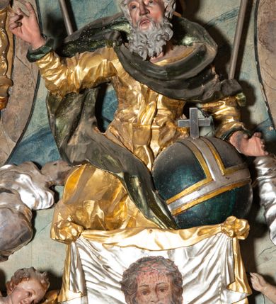 Zdjęcie nr 10: Ołtarz architektoniczny, trójosiowy, z wydzieloną częścią cokołową, jednokondygnacyjny, ze zwieńczeniem. Mensa drewniana tumbowa, ozdobiona nałożonymi płaskorzeźbionymi motywami rocaille’ów i roślinnymi. Po bokach mensy, w części cokołowej dwie bramki obejścia zamknięte półkoliście, w których osadzone na zawiasach drzwi jednoskrzydłowe z płycinami z malowanymi przedstawieniami świętych. W predelli oszklona trumienka z rzeźbą Chrystusa w grobie. Pole środkowe nastawy ujęte dwoma czworobocznymi filarami o kompozytowych kapitelach. Pola boczne wklęsłe i cofnięte od lica pola środkowego flankowane kolumnami o gładkich trzonach i kompozytowych kapitelach, umieszczonych na wysokich dwustopniowych postumentach ustawionych kątowo, zdobionych płycinami. Podpory dźwigają pełne belkowanie i gzyms, przerwane nad polem środkowym. W polu środkowym głęboka nisza w kształcie prostokąta stojącego zamkniętego łukiem wypukło-wklęsłym, w bogatym obramieniu. W niej rzeźba Pieta. Po bokach, na tle filarów, umieszczone dwa okazałe anioły w dynamicznych pozach, z rozłożonymi skrzydłami. Ponad niszą płaskorzeźbiona Chusta św. Weroniki rozpostarta przez dwa uskrzydlone putta ze stopami wspartymi na obłokach. W polach bocznych nastawy sferyczne płyciny w asymetrycznych złoconych obramieniach, na których tle umieszczone na konsolach rzeźby: Św. Jan Ewangelista (po lewej) i Św. Maria Magdalena (po prawej). Zwieńczenie w formie aedikuli ujętej wolutami i zwieńczonej półkoliście. Na tle aedikuli rzeźbione przedstawienie tronującego Boga Ojca, ponad głową którego Arma Christi; wokół putta i uskrzydlone główki aniołków. W osiach podpór rzeźby uskrzydlonych aniołów. Uszaki nastawy rzeźbione, ażurowe, złocone, z motywów rocaille’ów i kwiatów słonecznika. Struktura polichromowana na kolor szaro-niebieski, a trzony filarów i kolumn oraz tła płycin na czerwono, imitując marmur;  detale i ornamenty złocone; szaty rzeźb złocone i srebrzone; karnacje w kolorze naturalnym. 