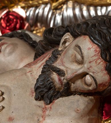 Zdjęcie nr 23: Ołtarz architektoniczny, trójosiowy, z wydzieloną częścią cokołową, jednokondygnacyjny, ze zwieńczeniem. Mensa drewniana tumbowa, ozdobiona nałożonymi płaskorzeźbionymi motywami rocaille’ów i roślinnymi. Po bokach mensy, w części cokołowej dwie bramki obejścia zamknięte półkoliście, w których osadzone na zawiasach drzwi jednoskrzydłowe z płycinami z malowanymi przedstawieniami świętych. W predelli oszklona trumienka z rzeźbą Chrystusa w grobie. Pole środkowe nastawy ujęte dwoma czworobocznymi filarami o kompozytowych kapitelach. Pola boczne wklęsłe i cofnięte od lica pola środkowego flankowane kolumnami o gładkich trzonach i kompozytowych kapitelach, umieszczonych na wysokich dwustopniowych postumentach ustawionych kątowo, zdobionych płycinami. Podpory dźwigają pełne belkowanie i gzyms, przerwane nad polem środkowym. W polu środkowym głęboka nisza w kształcie prostokąta stojącego zamkniętego łukiem wypukło-wklęsłym, w bogatym obramieniu. W niej rzeźba Pieta. Po bokach, na tle filarów, umieszczone dwa okazałe anioły w dynamicznych pozach, z rozłożonymi skrzydłami. Ponad niszą płaskorzeźbiona Chusta św. Weroniki rozpostarta przez dwa uskrzydlone putta ze stopami wspartymi na obłokach. W polach bocznych nastawy sferyczne płyciny w asymetrycznych złoconych obramieniach, na których tle umieszczone na konsolach rzeźby: Św. Jan Ewangelista (po lewej) i Św. Maria Magdalena (po prawej). Zwieńczenie w formie aedikuli ujętej wolutami i zwieńczonej półkoliście. Na tle aedikuli rzeźbione przedstawienie tronującego Boga Ojca, ponad głową którego Arma Christi; wokół putta i uskrzydlone główki aniołków. W osiach podpór rzeźby uskrzydlonych aniołów. Uszaki nastawy rzeźbione, ażurowe, złocone, z motywów rocaille’ów i kwiatów słonecznika. Struktura polichromowana na kolor szaro-niebieski, a trzony filarów i kolumn oraz tła płycin na czerwono, imitując marmur;  detale i ornamenty złocone; szaty rzeźb złocone i srebrzone; karnacje w kolorze naturalnym. 