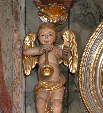 Zdjęcie nr 11: Prospekt organowy jednokondygnacyjny, trójosiowy, złożony z trzech prostopadłościennych segmentów z ryzalitami; środkowy najwyższy, na rzucie półkolisty, skrajne niższe, dwuboczne, dźwigające odcinki belkowania i profilowanego gzymsu; w zwieńczeniu owalne medaliony ujęte liśćmi akantu. Ryzality wypełnione piszczałkami, częściowo przesłoniętymi ażurową dekoracją. Prospekt ujęty ażurowymi uszakami z motywów roślinnych. Struktura polichromowana w kolorze drewna, ornamenty złocone.
