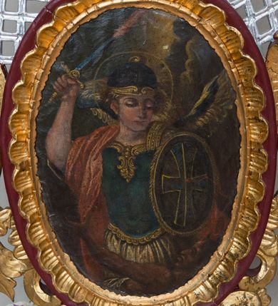 Zdjęcie nr 2: Feretron dwustronny ustawiony na prostopadłościennej podstawie zaopatrzonej w otwory na drążki do noszenia. Podstawa zwężająca się ku górze w formę niskiego cokołu, po bokach dekorowanego szeroką, karbowaną wstęgą. Na cokole osadzona jest owalna rama, dekorowana rocaille’owym fartuchem, w której umieszczony jest wizerunek św. Michała Archanioła, a na odwrociu św. Józefa Kalasantego. Zwieńczenie w formie esowato wygiętej i delikatnie karbowanej wstęgi, zakończonej po bokach dwoma spływami kwiatowymi. Od zewnątrz wstęga ozdobiona jest rocaille’m, a od wewnątrz połączona ze strukturą feretronu srebrzoną kratką. Na awersie obraz św. Michała Archanioła, ukazanego w dynamicznej pozie, strącającego szatana do piekła. Archanioł przedstawiony w postawie stojącej w półpostaci z podniesioną prawą ręką do góry, w której trzyma płomienisty miecz skierowany ostrzem ku górze, a w lewej owalną tarczę ozdobioną znakiem krzyża. Twarz trójkątna, z długim i prostym nosem, wzrokiem skierowanym w dół. Włosy średniej długości, jasne, rozwiane po bokach. Archanioł ubrany jest w zbroję legionisty rzymskiego: ma niebieską tunikę obszytą złotą lamówką na brzegu, hełm i czerwony płaszcz na prawym ramieniu; natomiast na plecach ma złote skrzydła. Na dole kompozycji ukazany jest szatan w pozycji leżącej z głową z prawej strony obrazu, lewą rękę wznoszący ku górze. Twarz podłużna z rogami na czole, karnacja ciemna. Ubrany jest w białą szatę, odsłaniającą nagi tors. Tło obrazu jest jednolite, ciemne, rozjaśnione w górnej części. Wokół głowy św. Michała znajduje się okrągły i złoty nimb. Po drugiej stronie feretronu umieszczony jest obraz św. Józefa Kalasantego. Święty ukazany jest delikatnie z prawej strony kompozycji, zwrócony w prawo w stronę gromadki dzieci. Święty na lewym ramieniu trzyma kilkuletnie dziecko, a prawą głaszcze po głowie nadbiegającego ku niemu chłopca w niebieskiej koszuli i żółtych spodniach. Święty Józef ubrany jest w czarny habit zakonu pijarów. Ma podłużne rysy twarzy z widoczną łysiną i siwymi włosami. Obraz malowany jest w zielono-żółtej tonacji. Tło jasnozielone, rozświetlone w górnej części. Podstawa feretronu malowana farbą olejną w kolorze jasnobrązowym, rama bordowa, detale i ornamentyka złocone i srebrzone. 


