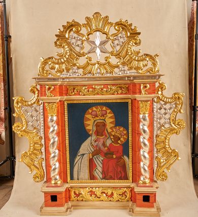 Zdjęcie nr 2: Feretron architektoniczny, ustawiony na cokole z wyodrębnionymi prostopadłościanami, w których znajdują się otwory na drążki, ujęty profilowanym gzymsem, w partii środkowej z dwóch stron dekorowany akantem. Rama w formie stojącego prostokąta, flankowana pilastrami oraz półkolumnami o skręconych trzonach, dźwigającymi belkowanie wyłamane na ich osi. Fryz zdobiony akantem. Feretron ujęty ażurowymi uszami utworzonymi z rocaille'u i kratki; zwieńczony szczytem złożonym z rocaille'u, wypełnionego ażurową kratką, z motywem sześcioramiennej gwiazdy w centrum na awersie oraz gorejącego serca na rewersie. Pole obrazowe w formie stojącego prostokąta. 
Na awersie przedstawienie Marki Boskiej z Dzieciątkiem. Maria ukazana w półpostaci, frontalnie, lewą ręką przytrzymuje Dzieciątko, w prawej, ugiętej trzyma trzy strzały. Twarz ma owalną, o regularnych rysach i ciemnej karnacji, małych oczach, krótkim nosie i niewielkich ustach. Ubrana jest w różową suknię, ze złoconą lamówką oraz jasnoniebieski, wzorzysty płaszcz, z czerwoną podszewką i złoconą lamówką, narzucony na głowę i ramiona. Na głowie ma koronę zamkniętą, wokół niej nimb i glorię. Dzieciątko ukazane w pozycji siedzącej, zwrócone w trzech czwartych w lewo, prawą rękę unosi w geście błogosławieństwa, lewą przytrzymuje na kolanach księgę. Twarz ma okrągłą, o ciemnej karnacji, małych oczach, krótkim nosie i pełnych ustach, okoloną krótkimi, ciemnobrązowymi włosami. Na głowie ma koronę zamkniętą, wokół niej nimb i glorię. Ubrane jest w czerwoną tunikę, ze złoconymi lamówkami. Postacie ukazane na jednolitym, niebieskim tle. 
Na rewersie przedstawienie Chrystusa w typie Ecce Homo, ukazanego do bioder, zwróconego w trzech czwartych w lewo, z uniesioną głową oraz ugiętymi i skrzyżowanymi z przodu rękami, przewiązanymi w nadgarstkach powrozem. Chrystus ma szczupłą, kwadratową twarz, o dużych oczach skierowanych w górę, krótkim nosie i pełnych, otwartych ustach z widocznymi zębami; okoloną krótką, jasną brodą oraz brązowymi włosami opadającymi na ramiona. Na głowie ma koronę cierniową, wokół niej złocony nimb. Przez biodra ma przewiązane obficie drapowane, białe perizonium, na ramiona ma narzucony srebrzysty płaszcz, z czerwoną podszewką i złoconą lamówką, zawiązany pod szyją niebieską wstęgą. Tors nagi, o lekko zarysowanej muskulaturze, bladej karnacji, z  zaznaczonymi, licznymi śladami męki. Chrystus ukazany na jednolitym, niebieskim tle. 