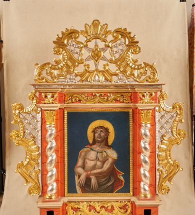 Zdjęcie nr 1: Feretron architektoniczny, ustawiony na cokole z wyodrębnionymi prostopadłościanami, w których znajdują się otwory na drążki, ujęty profilowanym gzymsem, w partii środkowej z dwóch stron dekorowany akantem. Rama w formie stojącego prostokąta, flankowana pilastrami oraz półkolumnami o skręconych trzonach, dźwigającymi belkowanie wyłamane na ich osi. Fryz zdobiony akantem. Feretron ujęty ażurowymi uszami utworzonymi z rocaille'u i kratki; zwieńczony szczytem złożonym z rocaille'u, wypełnionego ażurową kratką, z motywem sześcioramiennej gwiazdy w centrum na awersie oraz gorejącego serca na rewersie. Pole obrazowe w formie stojącego prostokąta. 
Na awersie przedstawienie Marki Boskiej z Dzieciątkiem. Maria ukazana w półpostaci, frontalnie, lewą ręką przytrzymuje Dzieciątko, w prawej, ugiętej trzyma trzy strzały. Twarz ma owalną, o regularnych rysach i ciemnej karnacji, małych oczach, krótkim nosie i niewielkich ustach. Ubrana jest w różową suknię, ze złoconą lamówką oraz jasnoniebieski, wzorzysty płaszcz, z czerwoną podszewką i złoconą lamówką, narzucony na głowę i ramiona. Na głowie ma koronę zamkniętą, wokół niej nimb i glorię. Dzieciątko ukazane w pozycji siedzącej, zwrócone w trzech czwartych w lewo, prawą rękę unosi w geście błogosławieństwa, lewą przytrzymuje na kolanach księgę. Twarz ma okrągłą, o ciemnej karnacji, małych oczach, krótkim nosie i pełnych ustach, okoloną krótkimi, ciemnobrązowymi włosami. Na głowie ma koronę zamkniętą, wokół niej nimb i glorię. Ubrane jest w czerwoną tunikę, ze złoconymi lamówkami. Postacie ukazane na jednolitym, niebieskim tle. 
Na rewersie przedstawienie Chrystusa w typie Ecce Homo, ukazanego do bioder, zwróconego w trzech czwartych w lewo, z uniesioną głową oraz ugiętymi i skrzyżowanymi z przodu rękami, przewiązanymi w nadgarstkach powrozem. Chrystus ma szczupłą, kwadratową twarz, o dużych oczach skierowanych w górę, krótkim nosie i pełnych, otwartych ustach z widocznymi zębami; okoloną krótką, jasną brodą oraz brązowymi włosami opadającymi na ramiona. Na głowie ma koronę cierniową, wokół niej złocony nimb. Przez biodra ma przewiązane obficie drapowane, białe perizonium, na ramiona ma narzucony srebrzysty płaszcz, z czerwoną podszewką i złoconą lamówką, zawiązany pod szyją niebieską wstęgą. Tors nagi, o lekko zarysowanej muskulaturze, bladej karnacji, z  zaznaczonymi, licznymi śladami męki. Chrystus ukazany na jednolitym, niebieskim tle. 