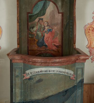 Zdjęcie nr 2: Konfesjonał na rzucie prostokąta zamkniętego od przodu łukiem segmentowym nadwieszonym, ustawiony na profilowanym cokole. Wybrzuszone przedpiersie ujęte lizenami z płycinami, zamknięte profilowanym gzymsem, u góry głównego pola przedpiersia namalowana banderola z napisem „NON MULTUM AB IMPECCABILI DISCEDIT, QVI PECCATUM UT DECET FATETUR. Aristoteles.”. Zaplecek z płyciną w polu w formie stojącego prostokąta zamkniętego łukiem półkolistym nadwieszonym, o wklęsłym dolnym odcinku. W polu malowana scena spowiedzi królowej u św. Jana Nepomucena. W lewej części sceny święty ukazany w pozycji siedzącej, na fotelu, prawą ręką wspiera się na podłokietniku, lewą podpiera głowę. Ubrany jest w sutannę, komżę, na ramionach ma stułę, a na głowie biret. W prawej części sceny ukazana jest klęcząca królowa, z lewą ręką złożoną na piersi, prawą wyciągniętą do góry. Ubrana jest w długą suknię, dołem czerwoną, w górnej części niebieską, przepasaną w talii, jasnobrązowy płaszcz, na głowie ma koronę otwartą. Scena ukazana jest we wnętrzu, w górnej części, po lewej, podwieszona zielona kurtyna. W dolnym podłuczu płyciny napis: „Solve Vincula Colli tui Captiva Filia / Sion. Ecclesia St 52”. 
Zaplecek ujęty ściankami bocznymi, w dolnej połowie szerokimi, zamkniętymi profilowanym gzymsem stanowiącym kontynuację gzymsu wieńczącego przedpiersie, z prostokątnymi drzwiczkami na zawiasach z lewej strony. W górnej połowie ścianki są węższe, o fantazyjnym wykroju, zakończone wolutą, z prostokątnymi prześwitami wypełnionymi kratką. Całość zwieńczona jest baldachimem na tym samym rzucie co korpus, ujętym z trzech stron belkowaniem. W partii frontowej fryzu malowana banderola z napisem: „PECCAVIMUS, INIQVITATEM FECIMUS, IMPIE EGIMUS. Danielis 9.”. Na podniebieniu baldachimu płycina w kształcie kwadratu wpisanego w czteroliść. W polu malowane przedstawienie aniołka w locie, który w prawej ręce trzyma język oraz liść palmy, w lewej zaś wieniec laurowy i kłódkę. Struktura konfesjonału polichromowana w sposób imitujący marmur w kolorze zielono-niebieskim, cokół, gzymsy i profile polichromowana w sposób imitujący marmur w kolorze jasnoczerwonym. 
