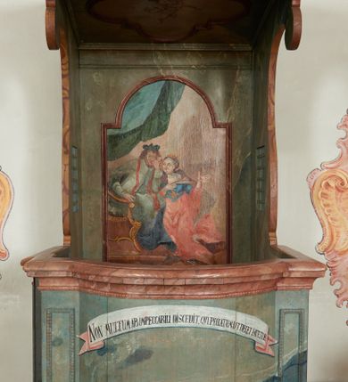 Zdjęcie nr 1: Konfesjonał na rzucie prostokąta zamkniętego od przodu łukiem segmentowym nadwieszonym, ustawiony na profilowanym cokole. Wybrzuszone przedpiersie ujęte lizenami z płycinami, zamknięte profilowanym gzymsem, u góry głównego pola przedpiersia namalowana banderola z napisem „NON MULTUM AB IMPECCABILI DISCEDIT, QVI PECCATUM UT DECET FATETUR. Aristoteles.”. Zaplecek z płyciną w polu w formie stojącego prostokąta zamkniętego łukiem półkolistym nadwieszonym, o wklęsłym dolnym odcinku. W polu malowana scena spowiedzi królowej u św. Jana Nepomucena. W lewej części sceny święty ukazany w pozycji siedzącej, na fotelu, prawą ręką wspiera się na podłokietniku, lewą podpiera głowę. Ubrany jest w sutannę, komżę, na ramionach ma stułę, a na głowie biret. W prawej części sceny ukazana jest klęcząca królowa, z lewą ręką złożoną na piersi, prawą wyciągniętą do góry. Ubrana jest w długą suknię, dołem czerwoną, w górnej części niebieską, przepasaną w talii, jasnobrązowy płaszcz, na głowie ma koronę otwartą. Scena ukazana jest we wnętrzu, w górnej części, po lewej, podwieszona zielona kurtyna. W dolnym podłuczu płyciny napis: „Solve Vincula Colli tui Captiva Filia / Sion. Ecclesia St 52”. 
Zaplecek ujęty ściankami bocznymi, w dolnej połowie szerokimi, zamkniętymi profilowanym gzymsem stanowiącym kontynuację gzymsu wieńczącego przedpiersie, z prostokątnymi drzwiczkami na zawiasach z lewej strony. W górnej połowie ścianki są węższe, o fantazyjnym wykroju, zakończone wolutą, z prostokątnymi prześwitami wypełnionymi kratką. Całość zwieńczona jest baldachimem na tym samym rzucie co korpus, ujętym z trzech stron belkowaniem. W partii frontowej fryzu malowana banderola z napisem: „PECCAVIMUS, INIQVITATEM FECIMUS, IMPIE EGIMUS. Danielis 9.”. Na podniebieniu baldachimu płycina w kształcie kwadratu wpisanego w czteroliść. W polu malowane przedstawienie aniołka w locie, który w prawej ręce trzyma język oraz liść palmy, w lewej zaś wieniec laurowy i kłódkę. Struktura konfesjonału polichromowana w sposób imitujący marmur w kolorze zielono-niebieskim, cokół, gzymsy i profile polichromowana w sposób imitujący marmur w kolorze jasnoczerwonym. 
